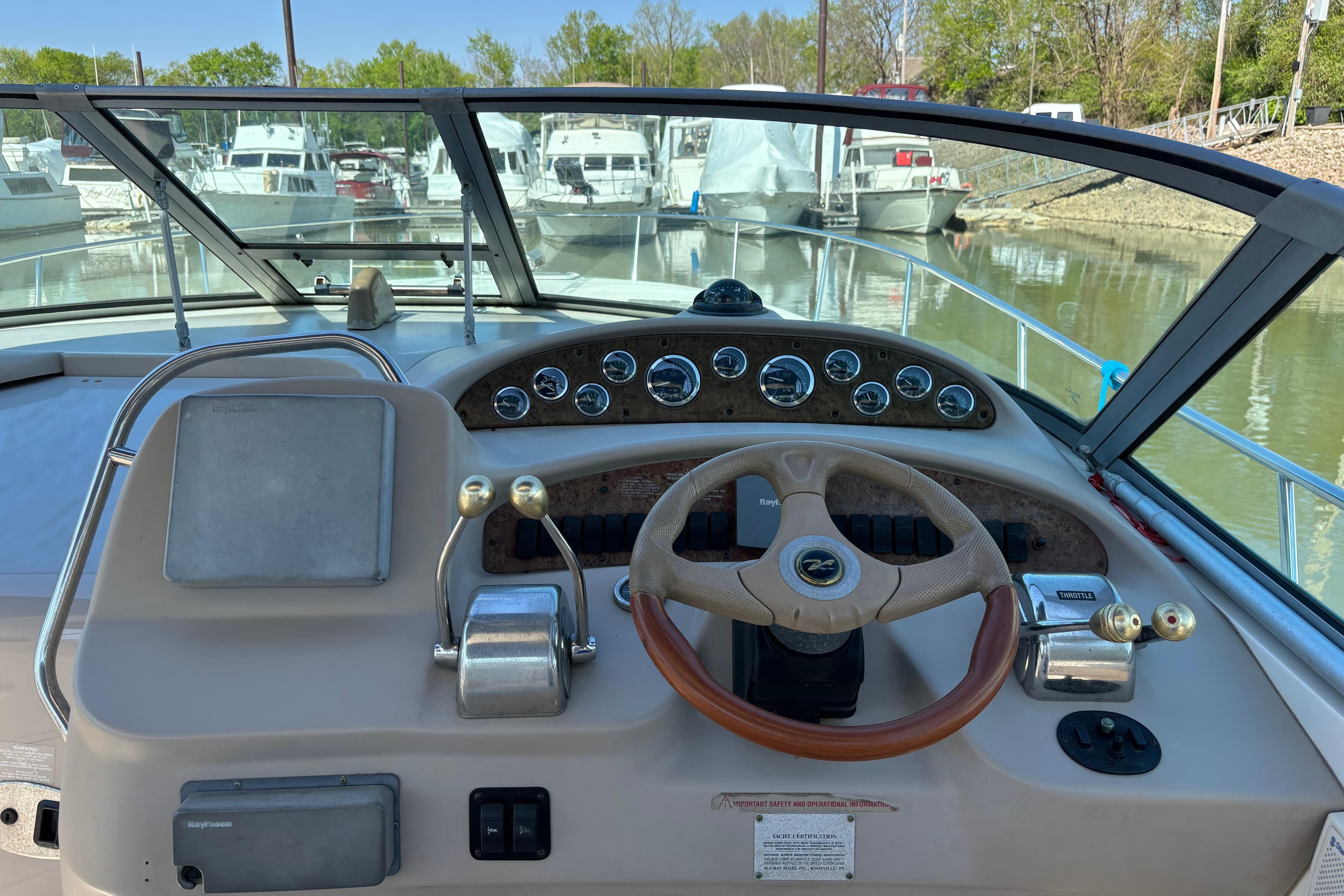 Helm of 2001 Sea Ray 340 Sundancer with steering wheel and control panel, docked at marina.