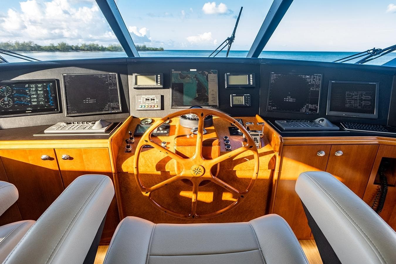 Pilothouse of 2007 Westport 112 yacht with wooden steering wheel and navigation screens.