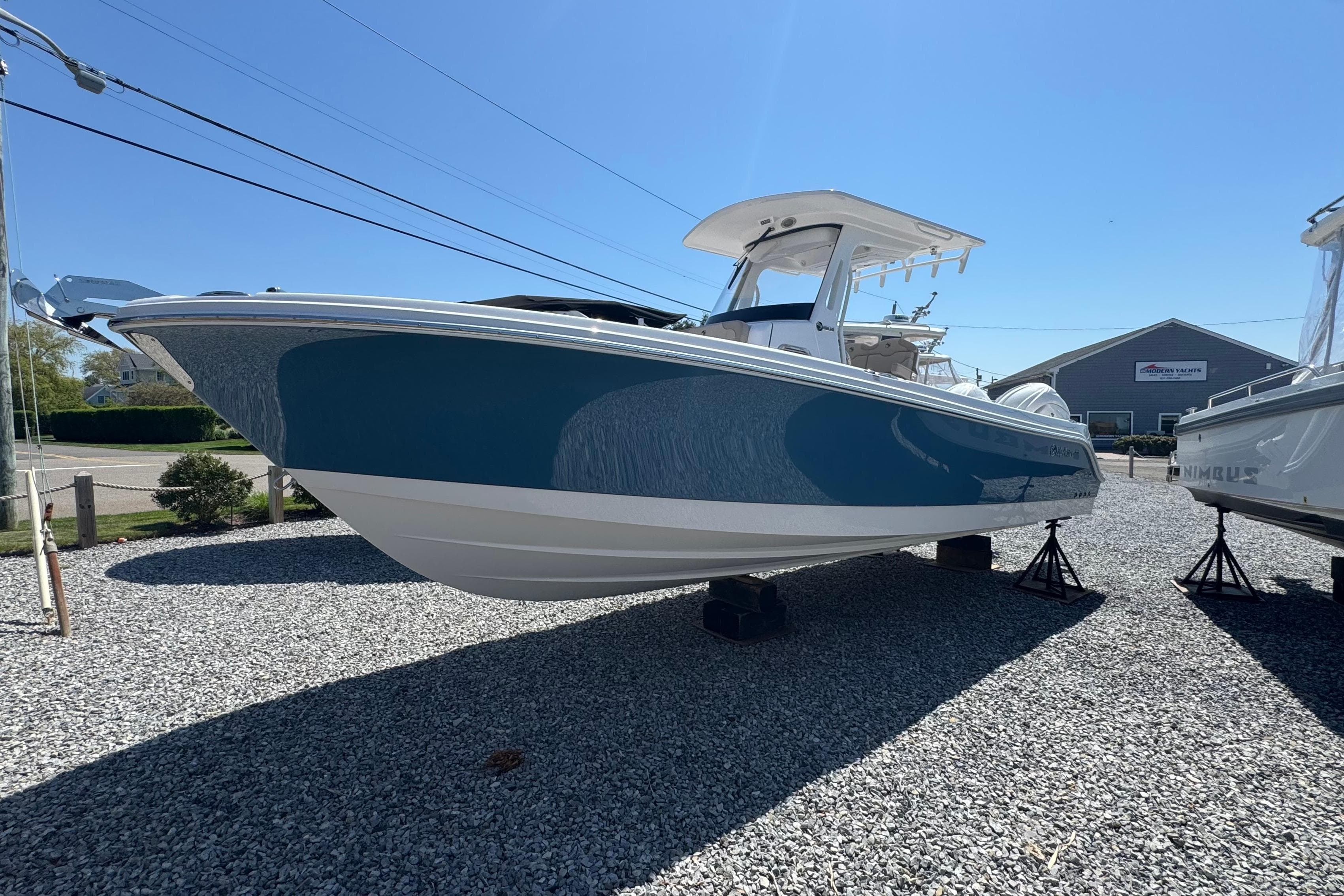 2026 Edgewater 262CC boat displayed outdoors on gravel lot under clear blue sky.