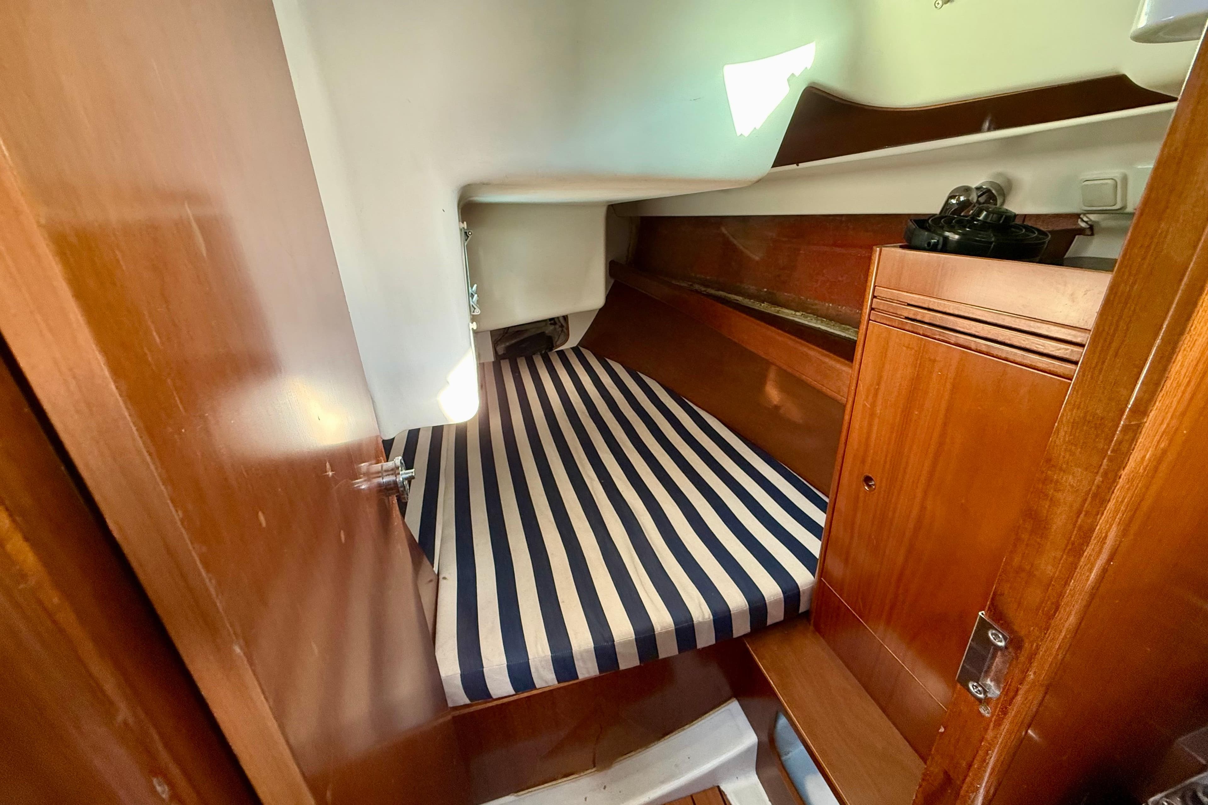 Cozy cabin interior of 2005 Beneteau First 36.7 sailboat with striped bedding.