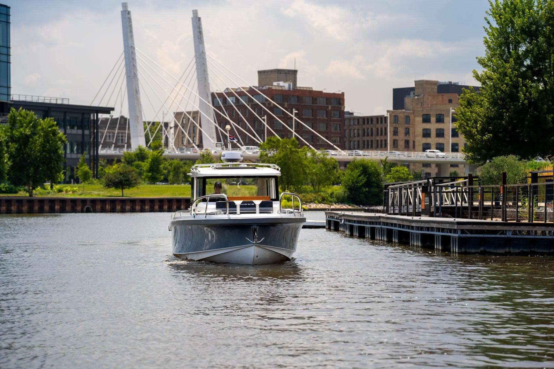 2025 Nimbus Commuter 9 boat cruising near urban waterfront with modern bridge in background.