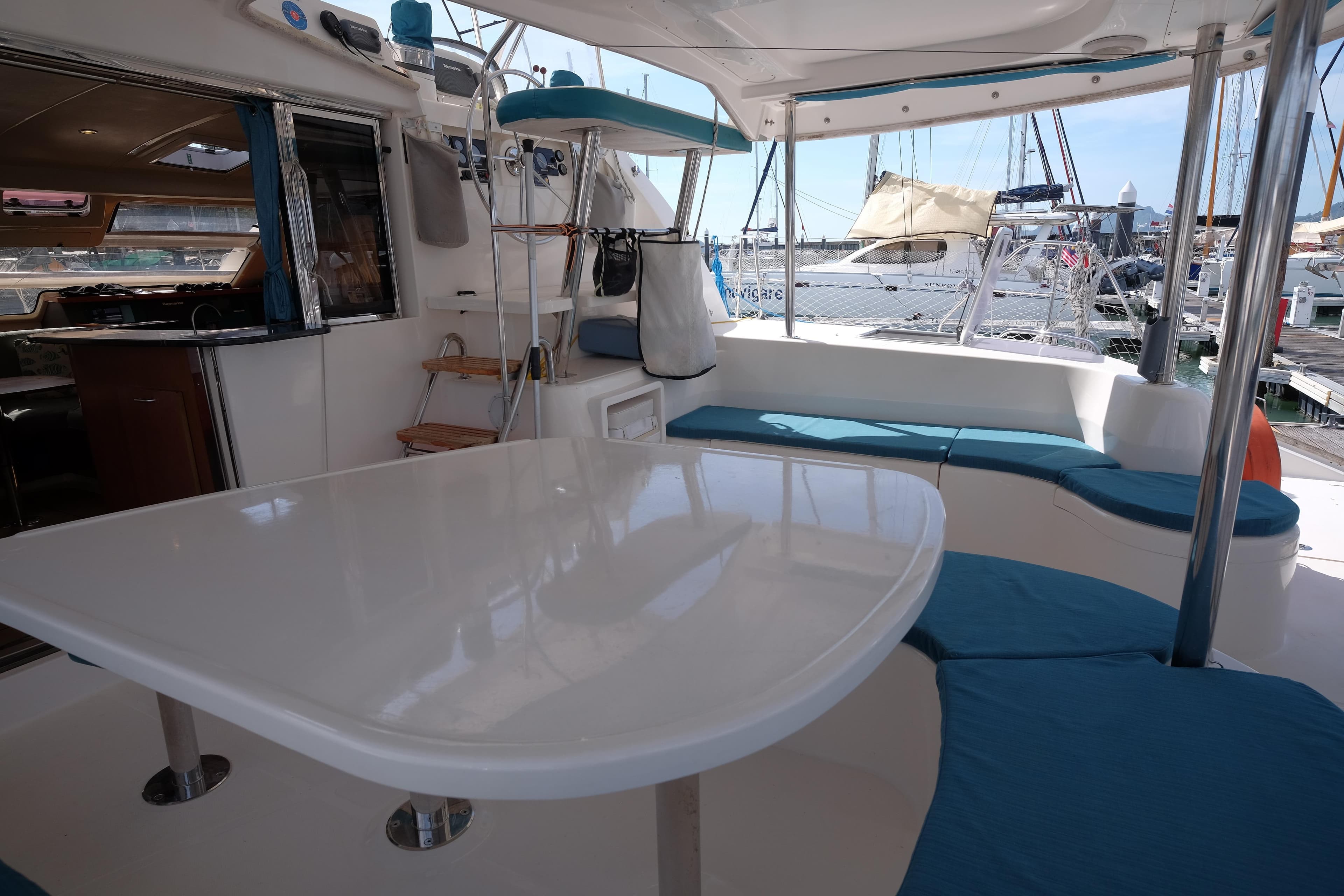 Spacious deck of 2009 Leopard 46 yacht with seating and table, docked at marina.