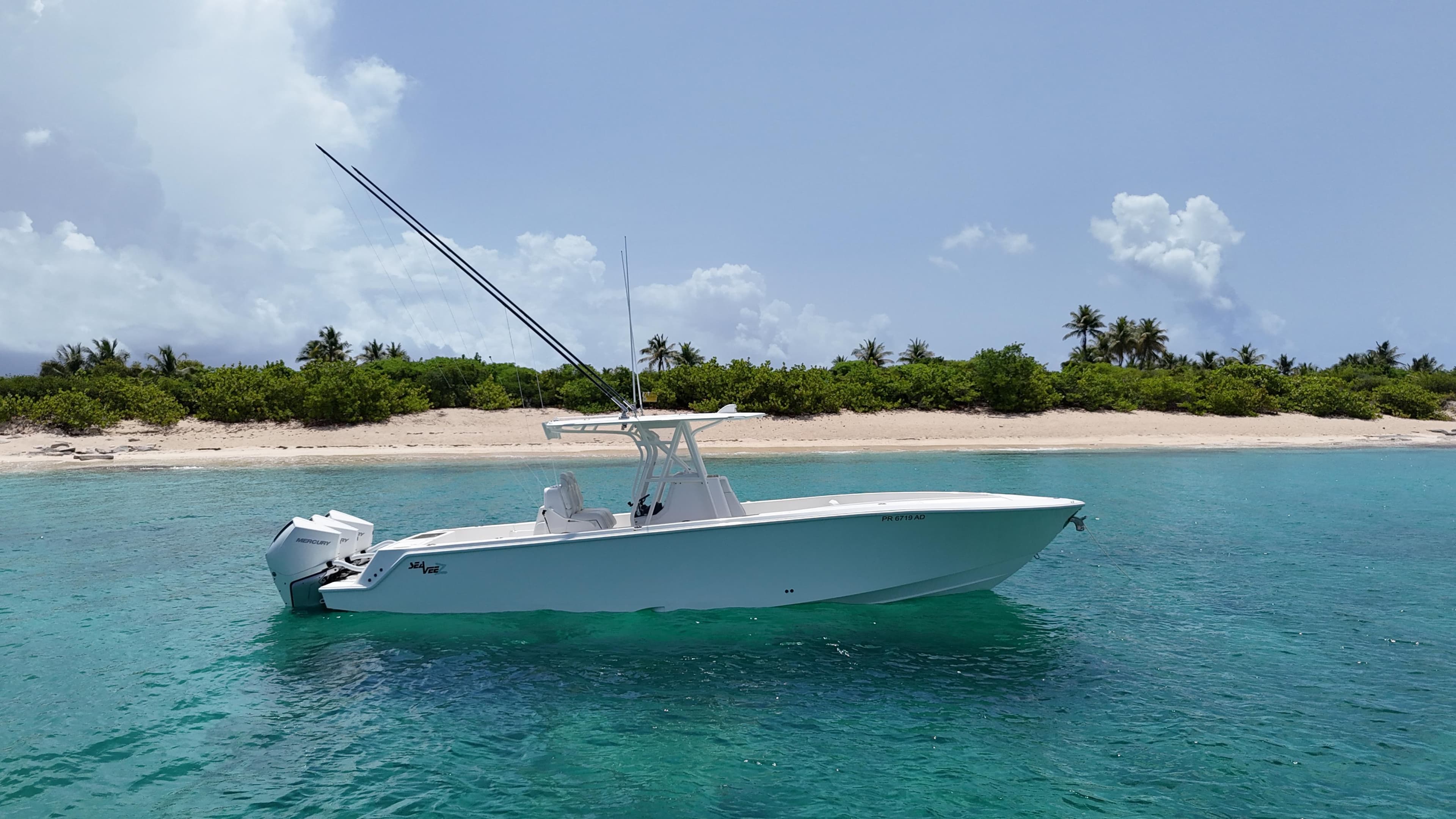 2024 SeaVee 340Z boat in clear turquoise water near a tropical beach.