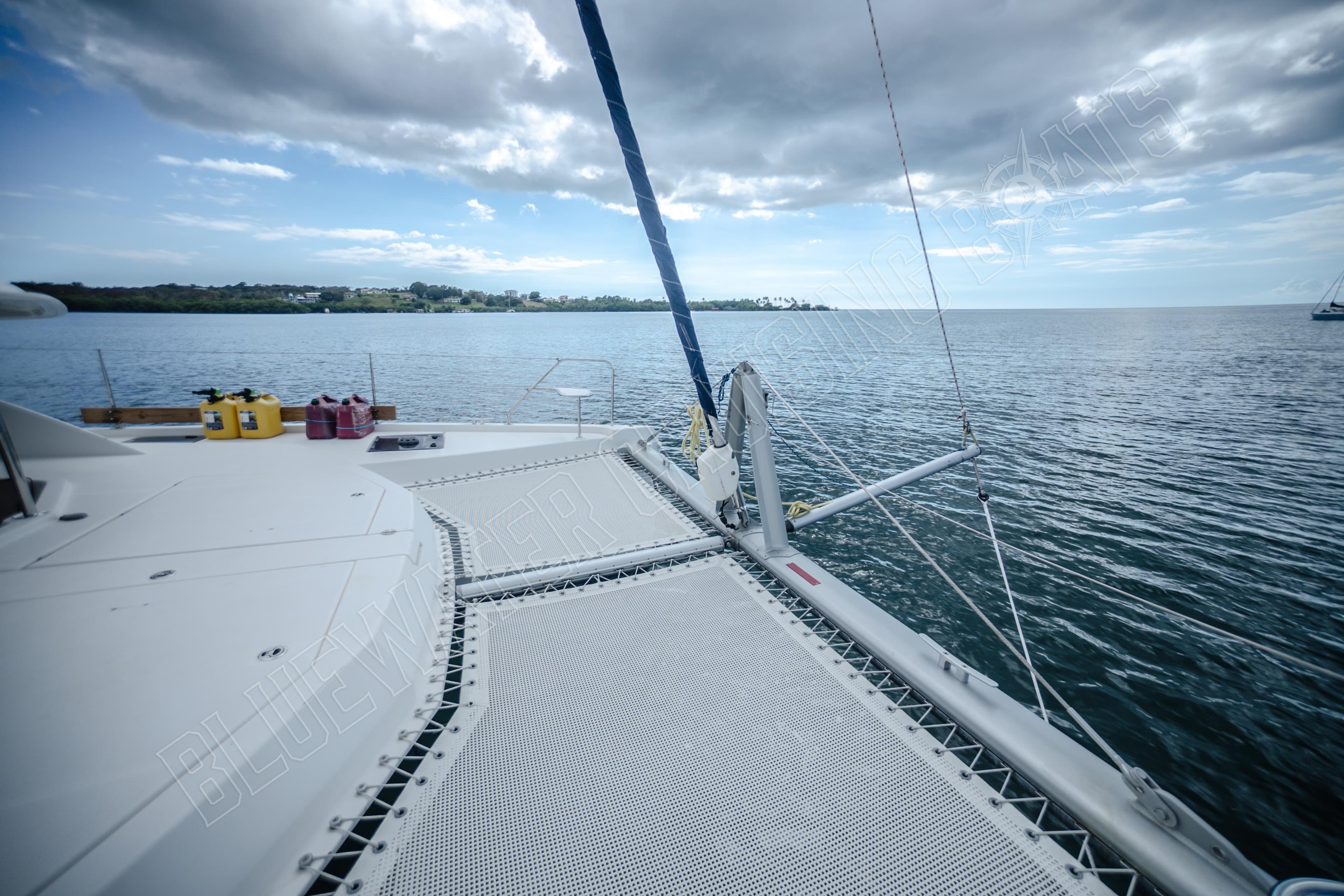 Catamaran deck view on Leopard 48, 2015 model, overlooking calm sea and cloudy sky.