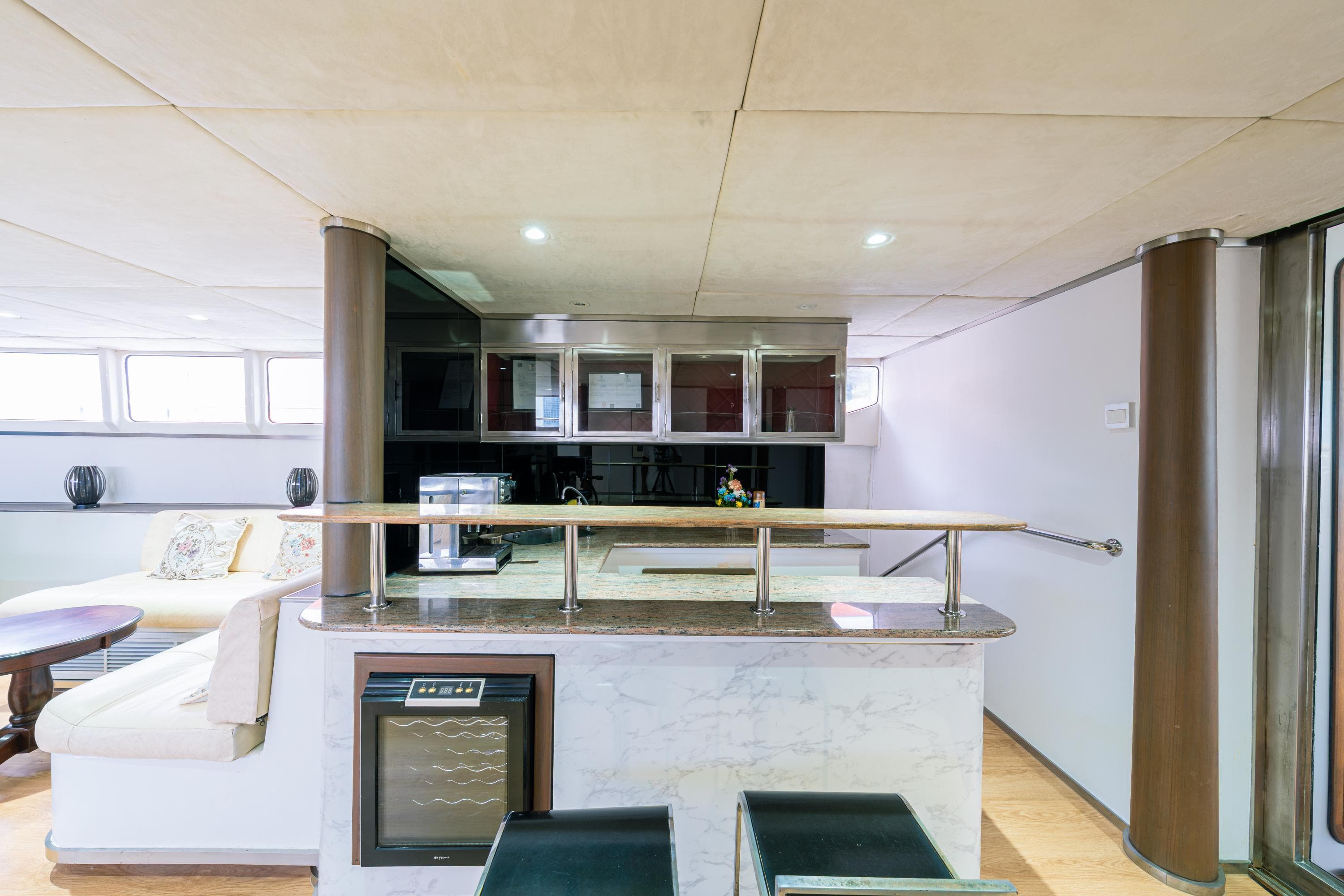 Luxurious yacht interior with modern kitchen, bar area, and comfortable seating, Custom Courage 82, 2023.