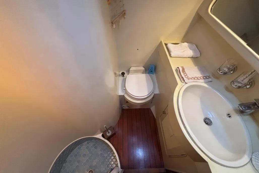 Compact bathroom in a 1988 Jongert 2000s yacht, featuring a toilet, sink, and shower.