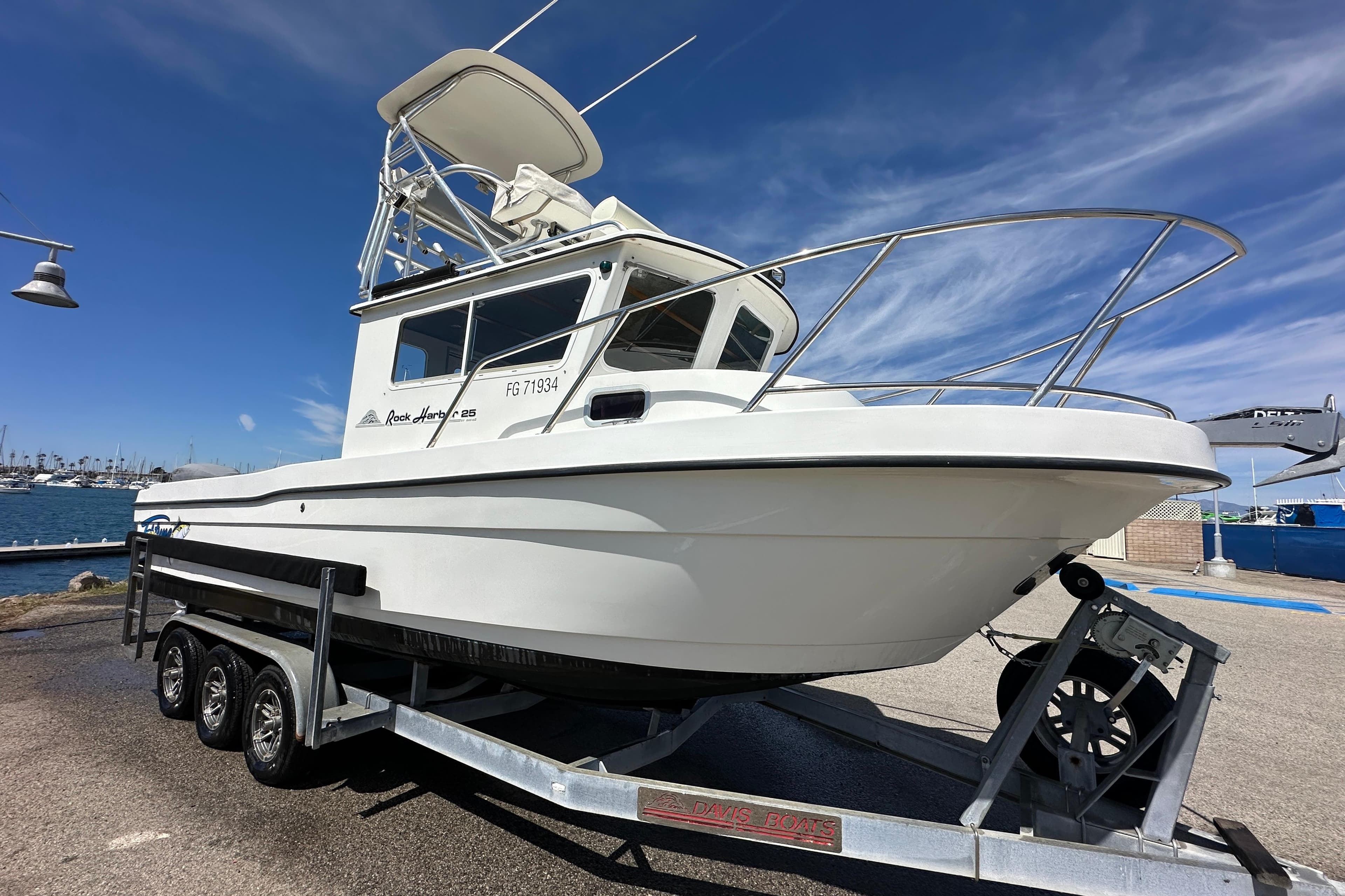 2012 Davis Rock Harbor 25 boat on trailer, dockside with clear blue sky.