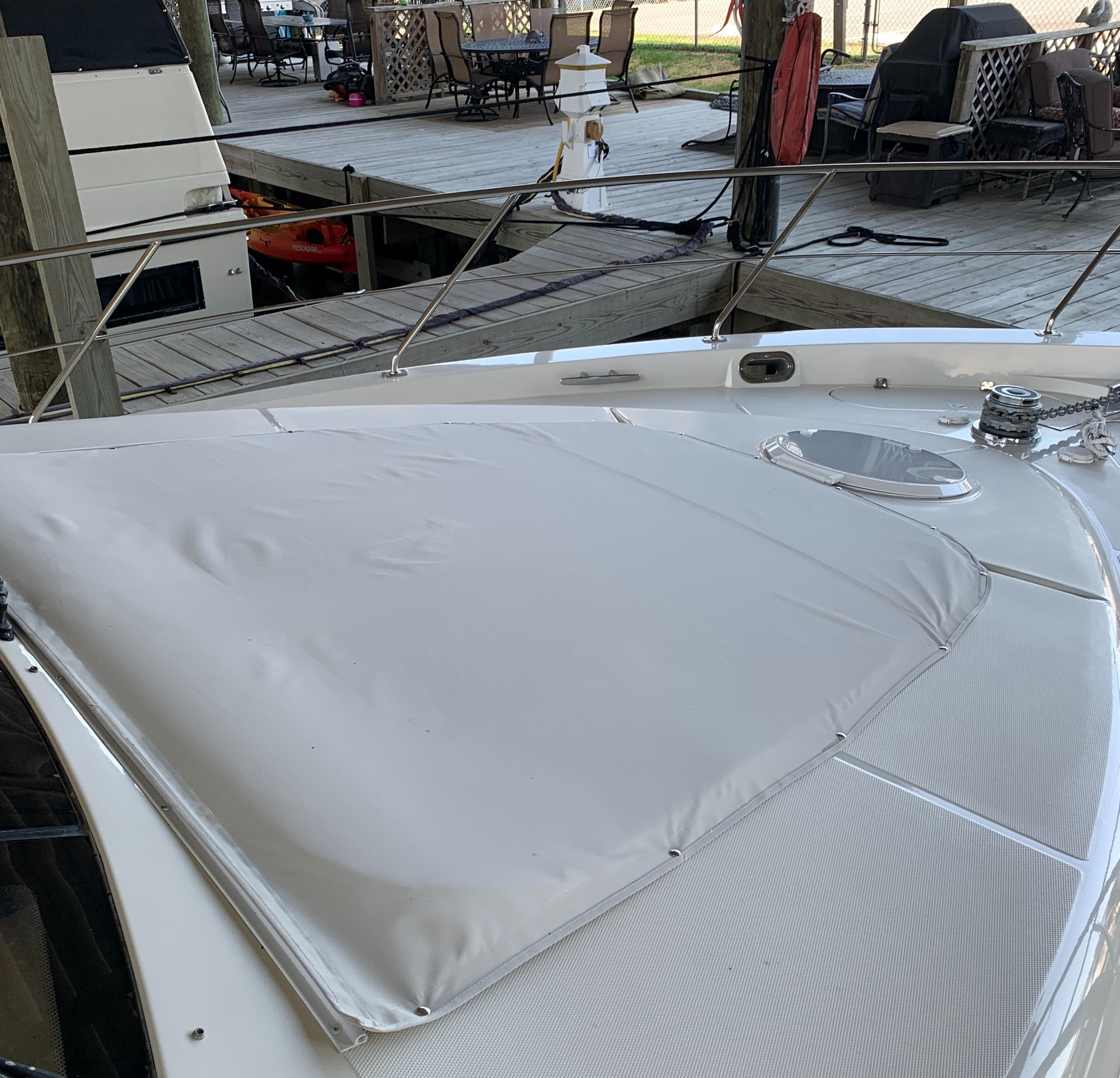 2007 Carver 56 Voyager yacht deck with sunpad, docked near outdoor seating area.