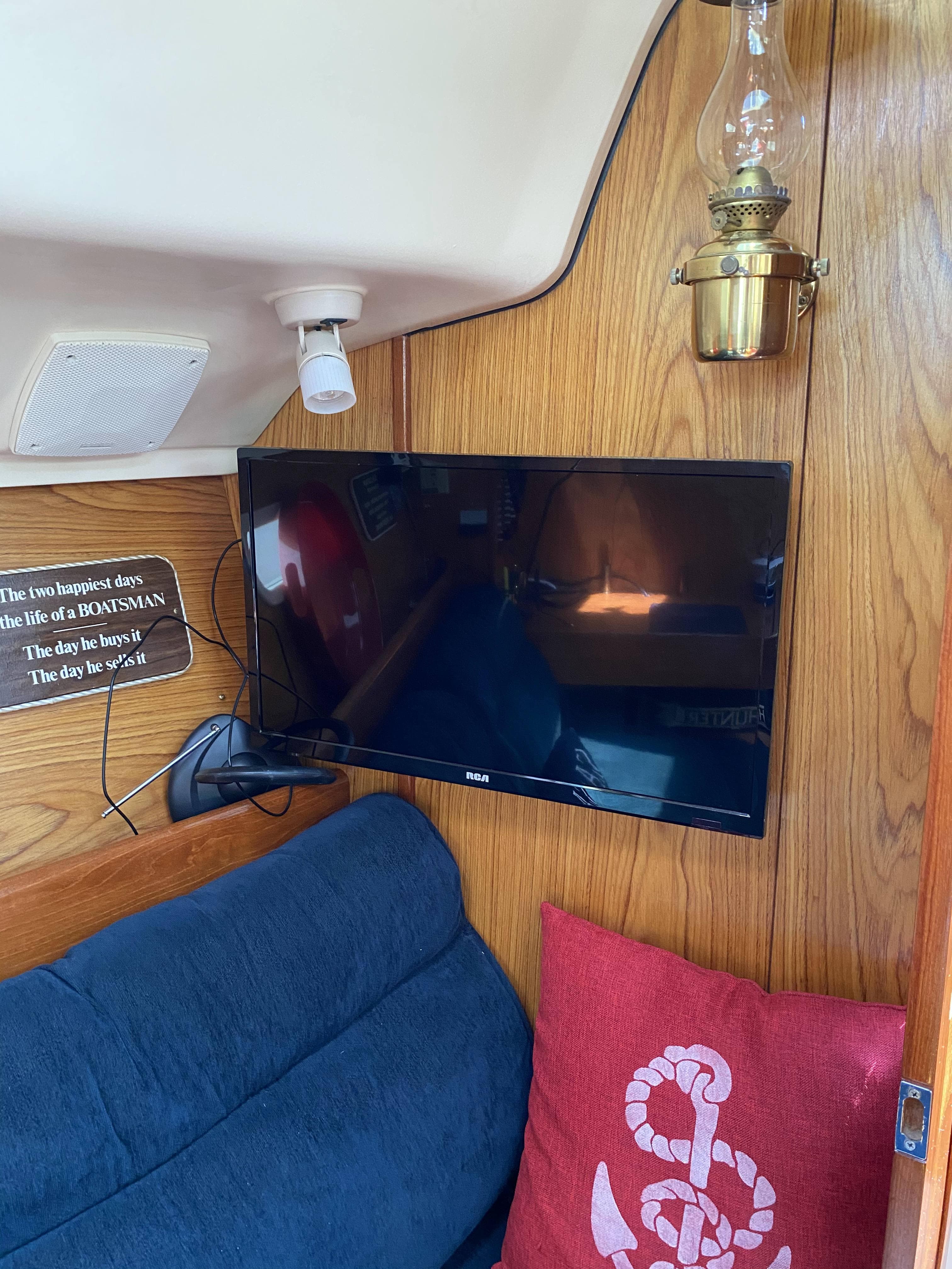 Interior of a 2001 Hunter 320 sailboat with TV, lamp, and nautical decor.
