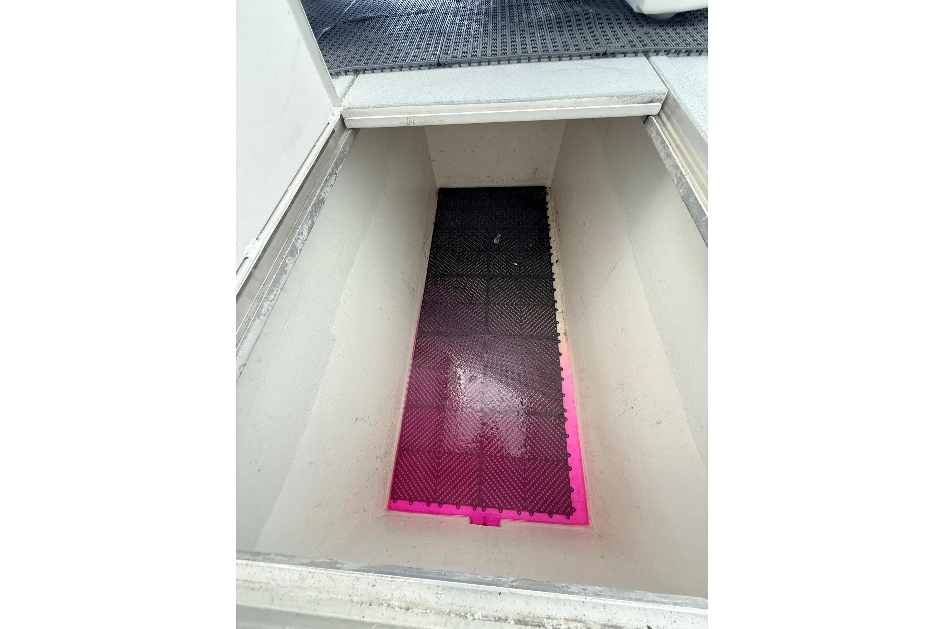 Open storage compartment on 2025 Wesmac 42 boat with pink and black flooring.