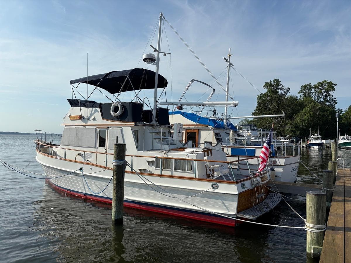 1986 Grand Banks 36 Classic yacht docked at marina, featuring American flag and calm waters.