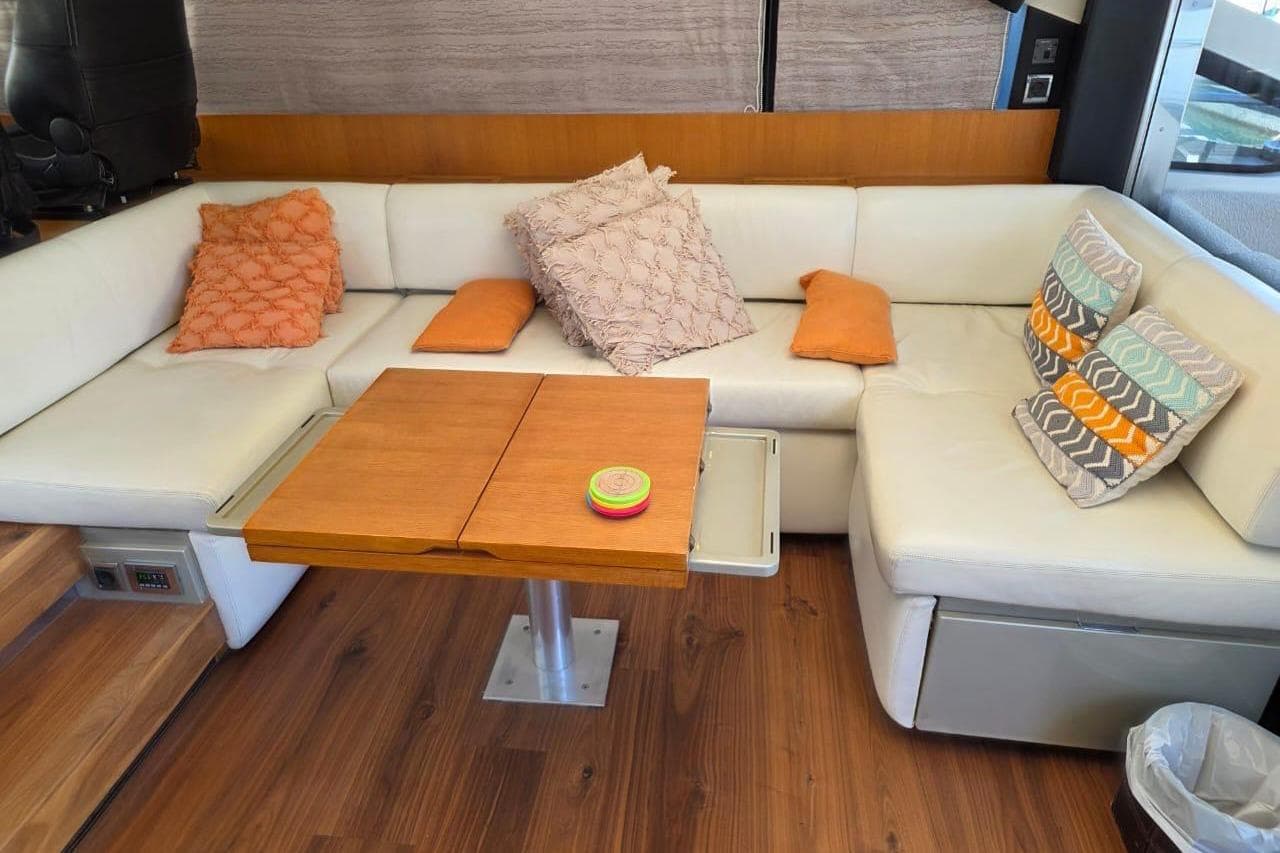 Luxurious interior of 2013 Fairline Targa 62 GT yacht with cozy seating and wooden table.