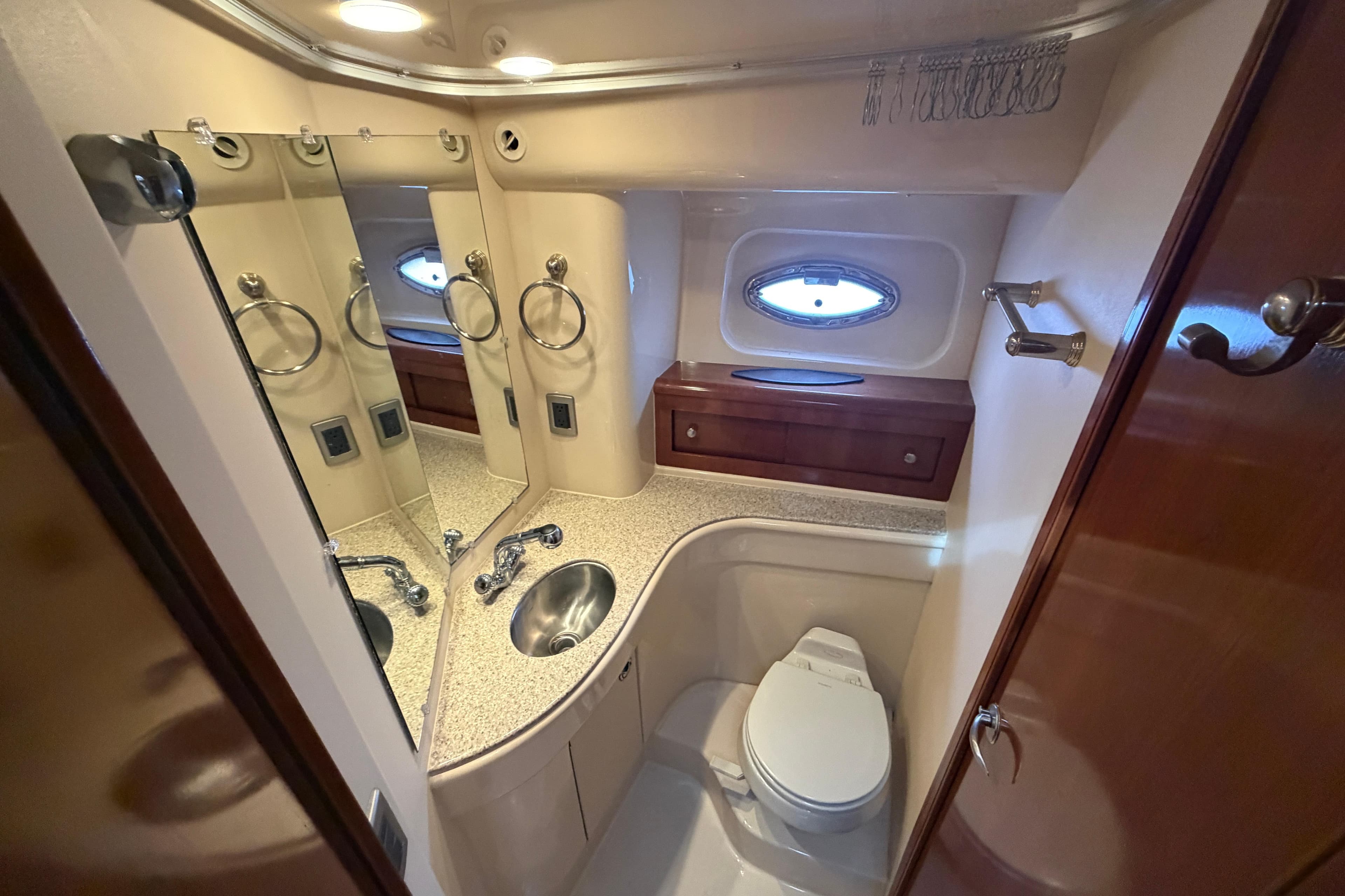 Luxurious bathroom in 2006 Meridian 411 Sedan yacht with modern fixtures and porthole window.