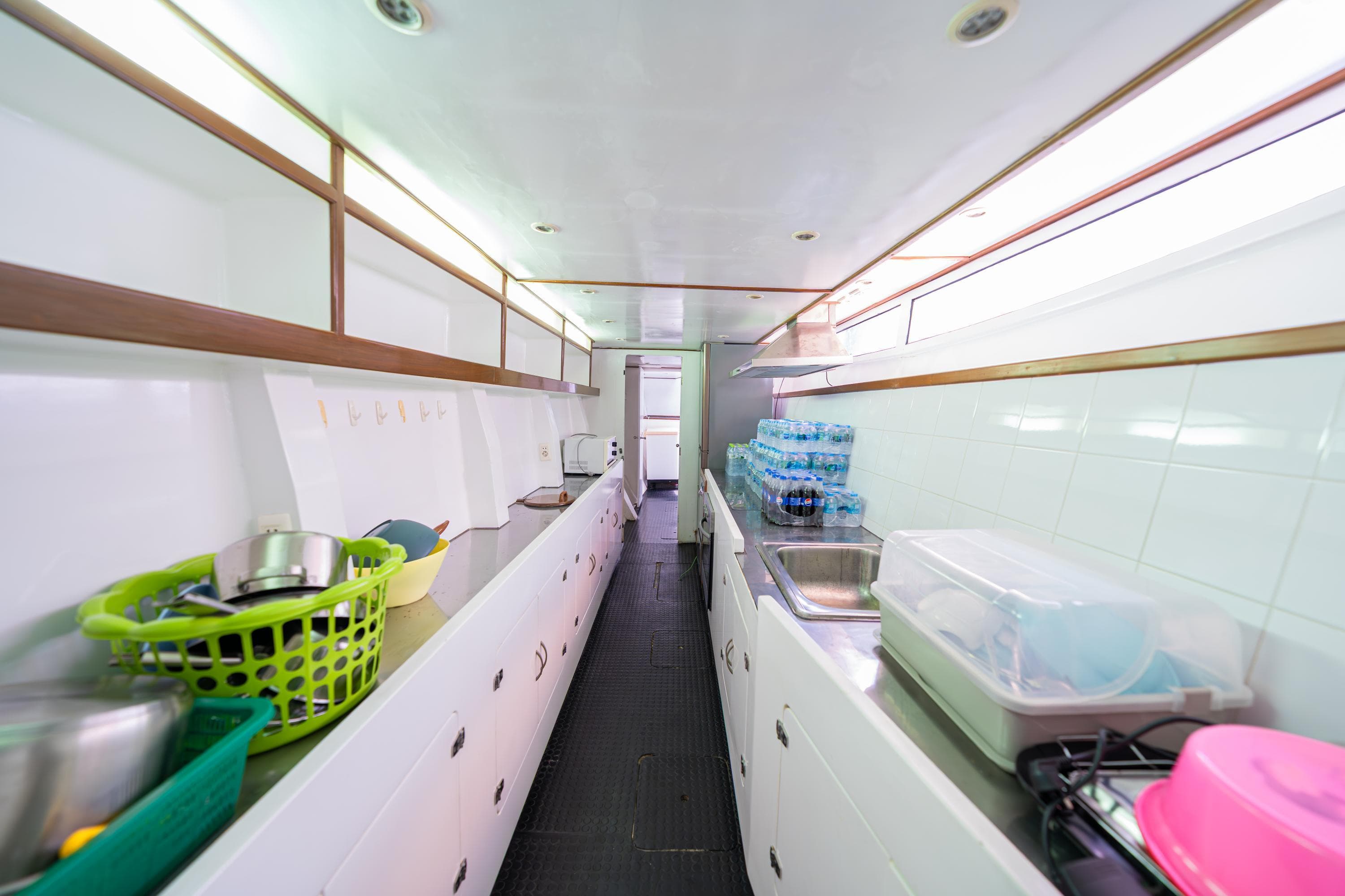 Modern mobile kitchen interior with white cabinets, sinks, and storage baskets, in a Custom Courage 82, 2023.