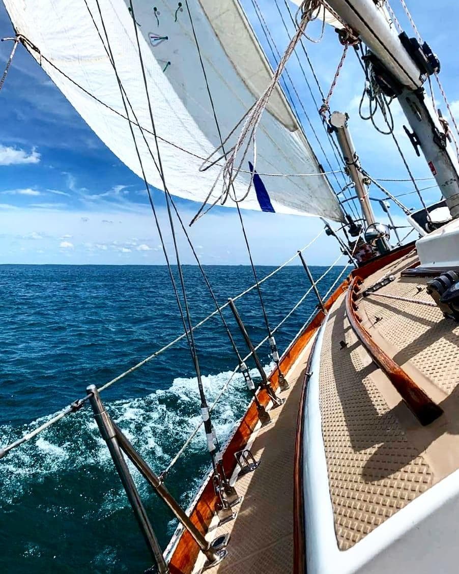Sailing on a 1981 Shannon 28 yacht, gliding through clear blue ocean waters.