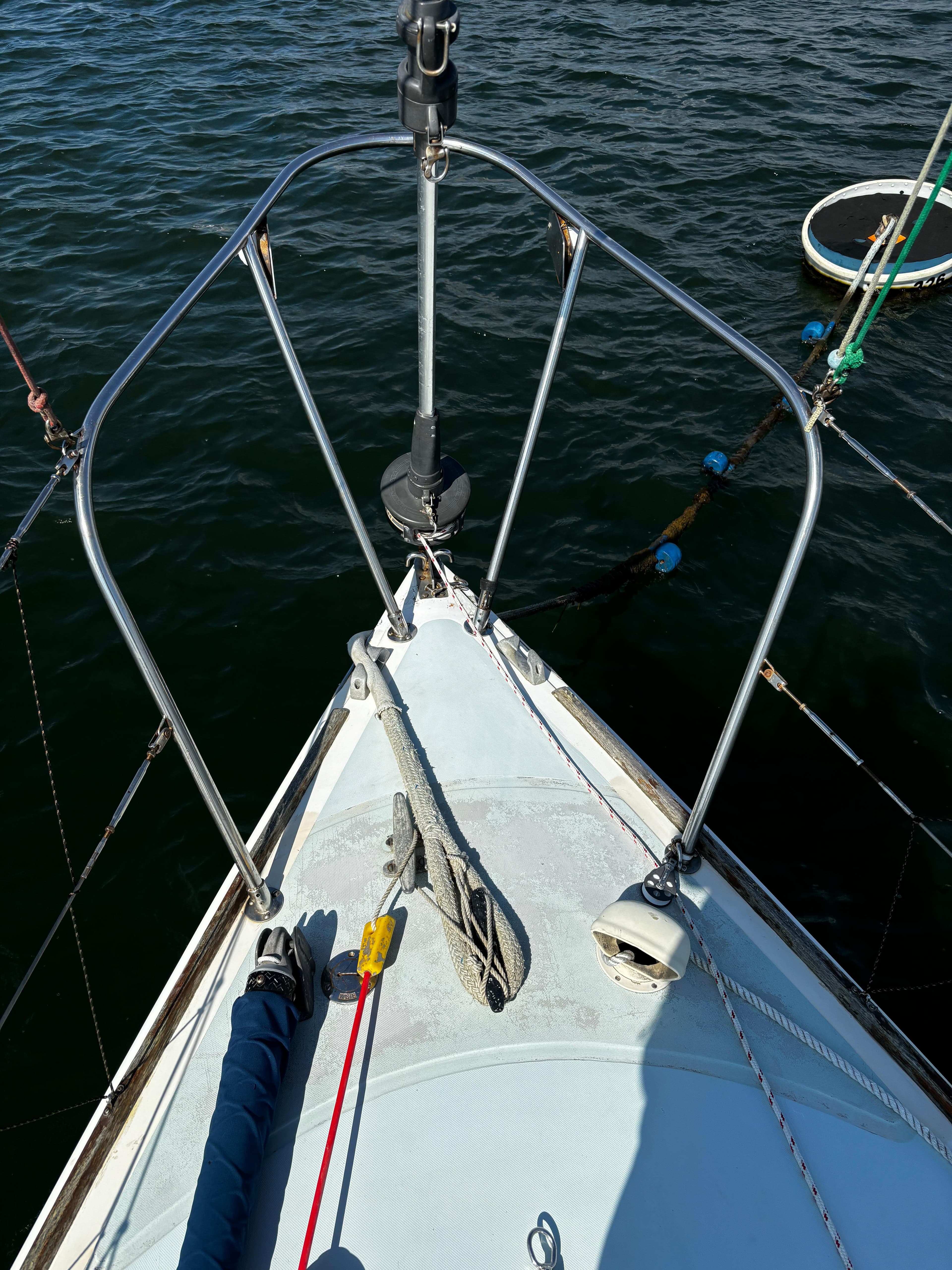 Bow of 1982 J Boats 30 sailboat with ropes and anchor, on calm water.