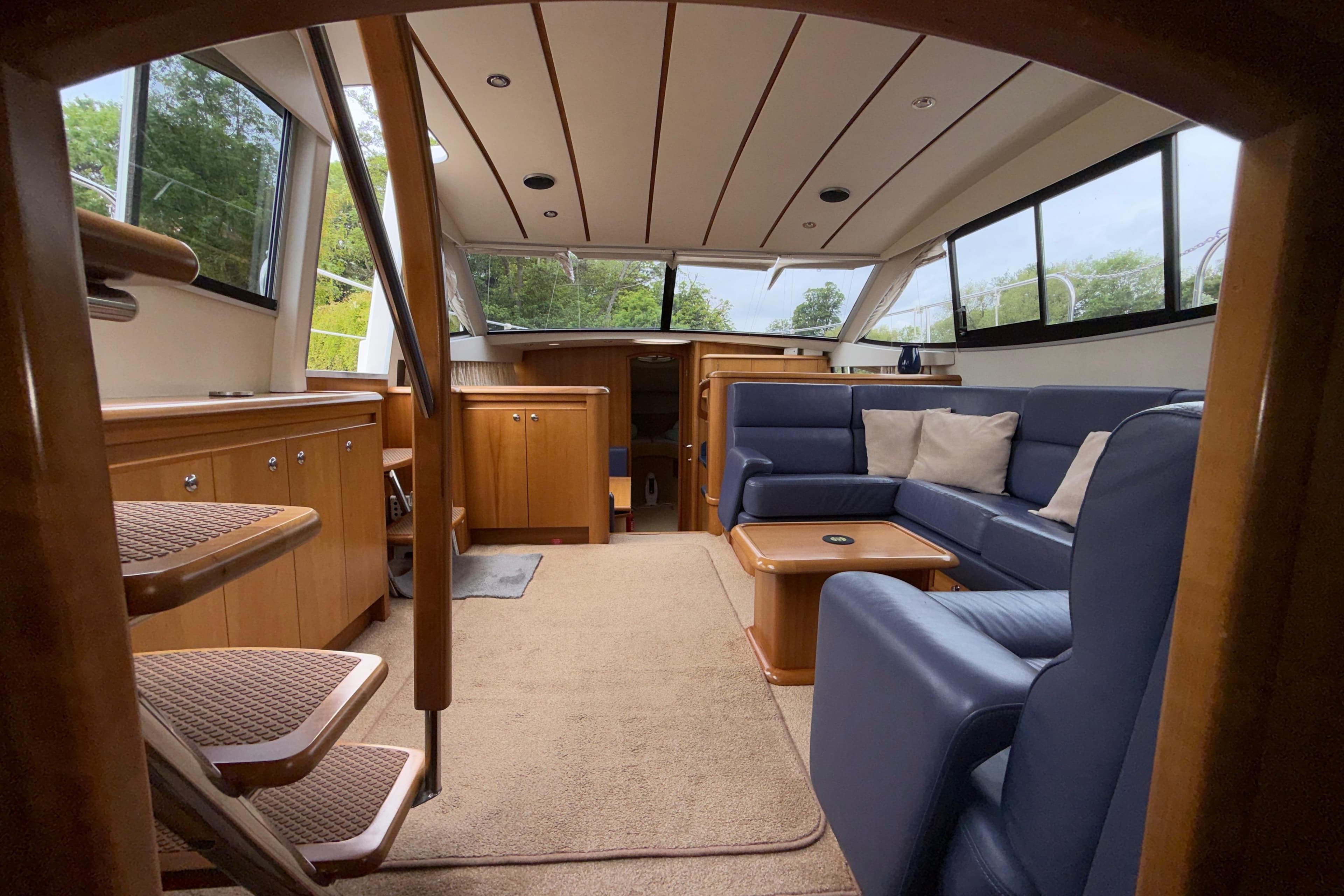 Luxurious interior of a 2004 Broom 42 CL yacht with blue seating and wooden cabinetry.