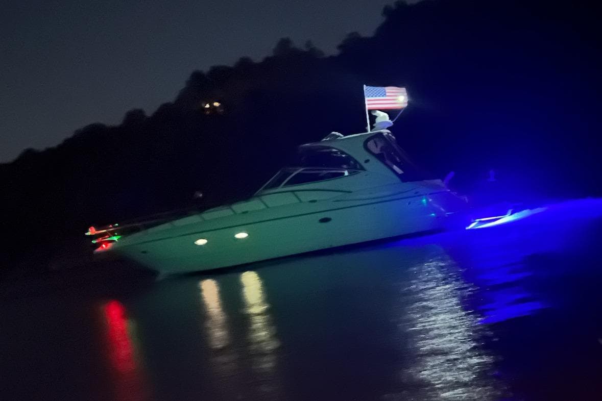 2003 Cruisers Yachts 4370 Express illuminated at night with American flag.