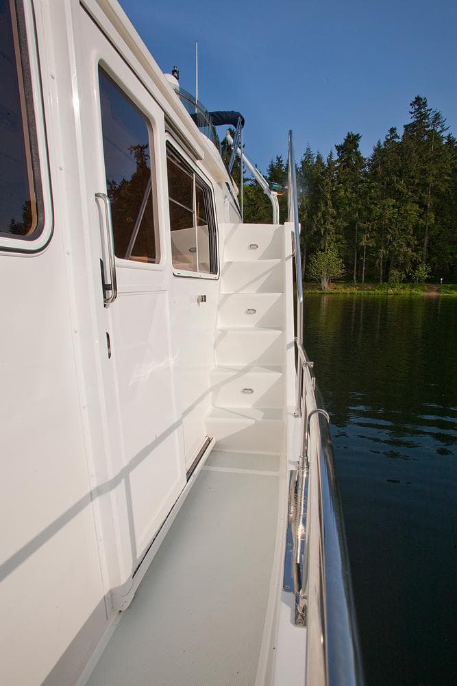 2026 Helmsman Trawlers 43E Pilothouse yacht exterior with stairs and scenic water view.