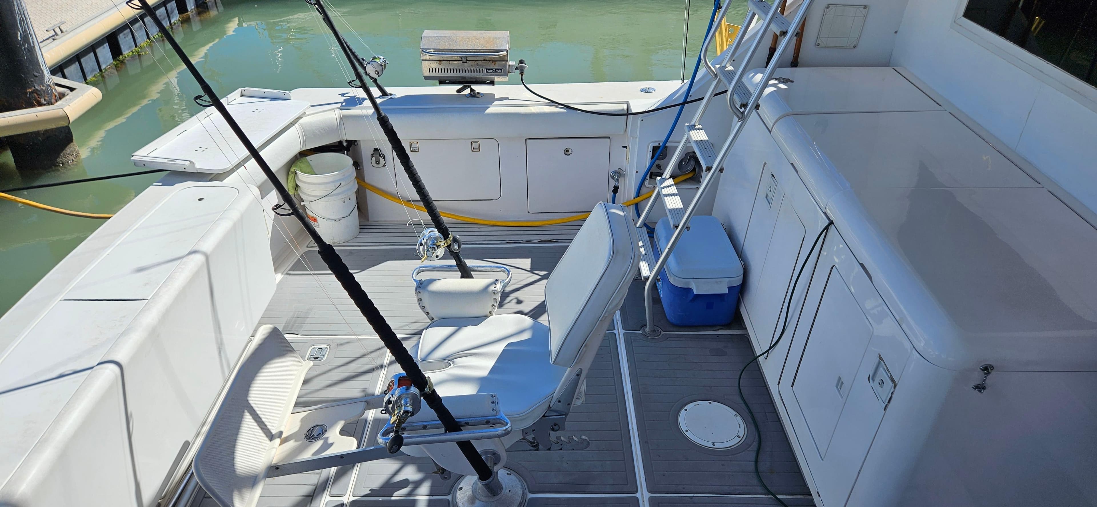 1995 Bertram Convertible boat deck with fishing rods and seating, docked in calm waters.