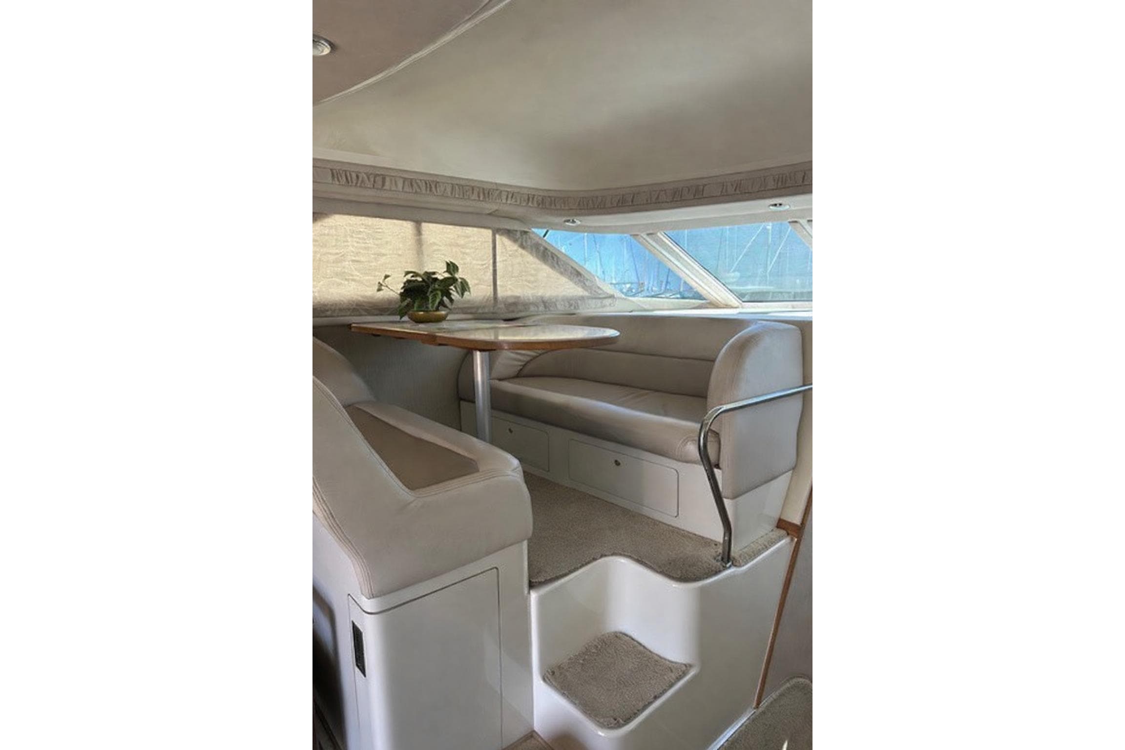 Interior of 1996 Sea Ray 400 Sedan Bridge with seating and table, featuring a potted plant.