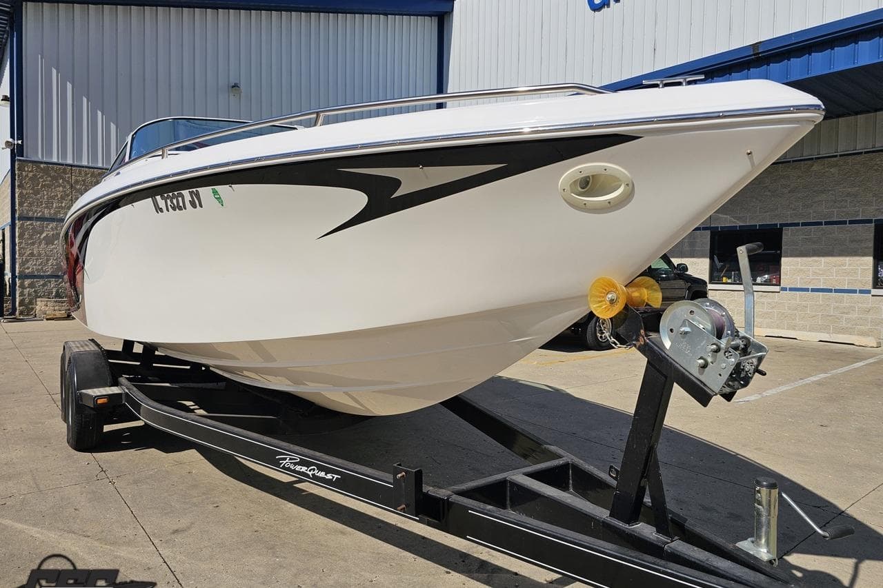 2006 Powerquest 240 Ultra LX boat on trailer, parked outside a building.