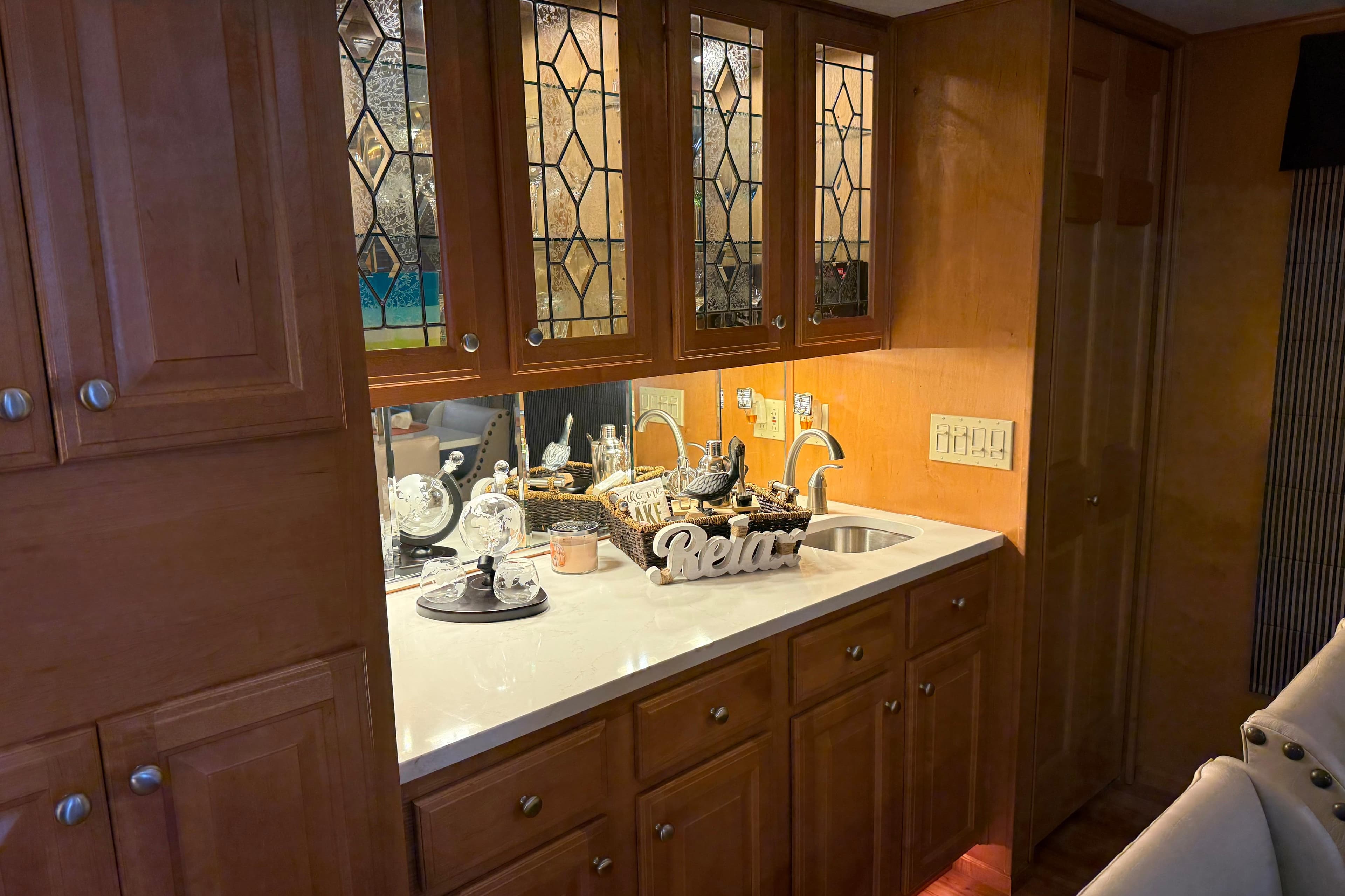 Cozy kitchen area in 2001 Sharpe 80 X 18 houseboat with wooden cabinets and decorative glass.