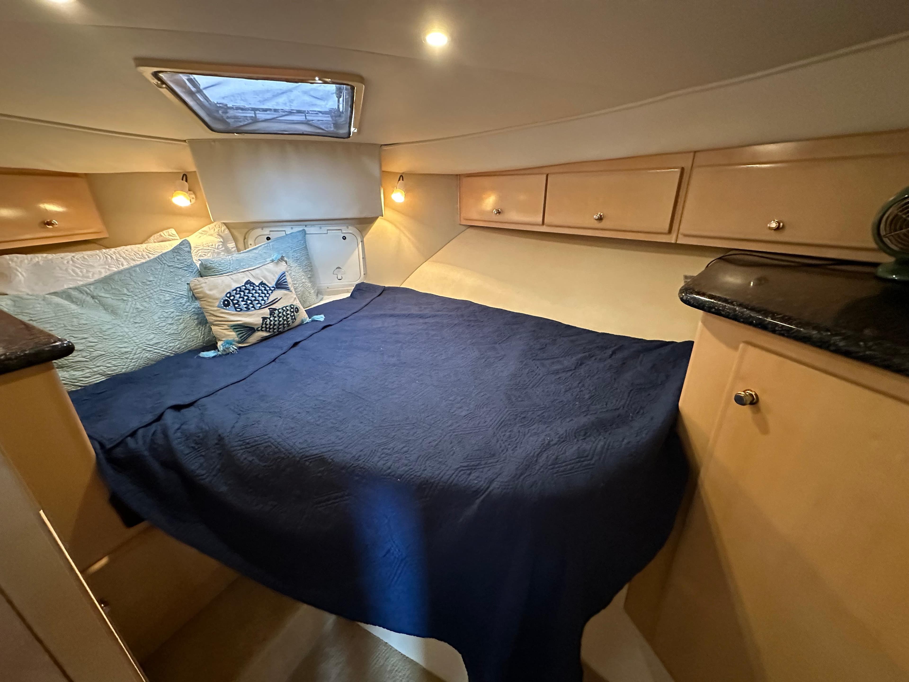 Cozy bedroom in a 2000 Carver 406 Motor Yacht with blue bedding and wooden cabinets.