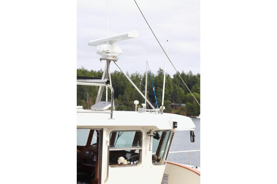 1996 Nordhavn 46 yacht bridge with radar, docked near forested shoreline.
