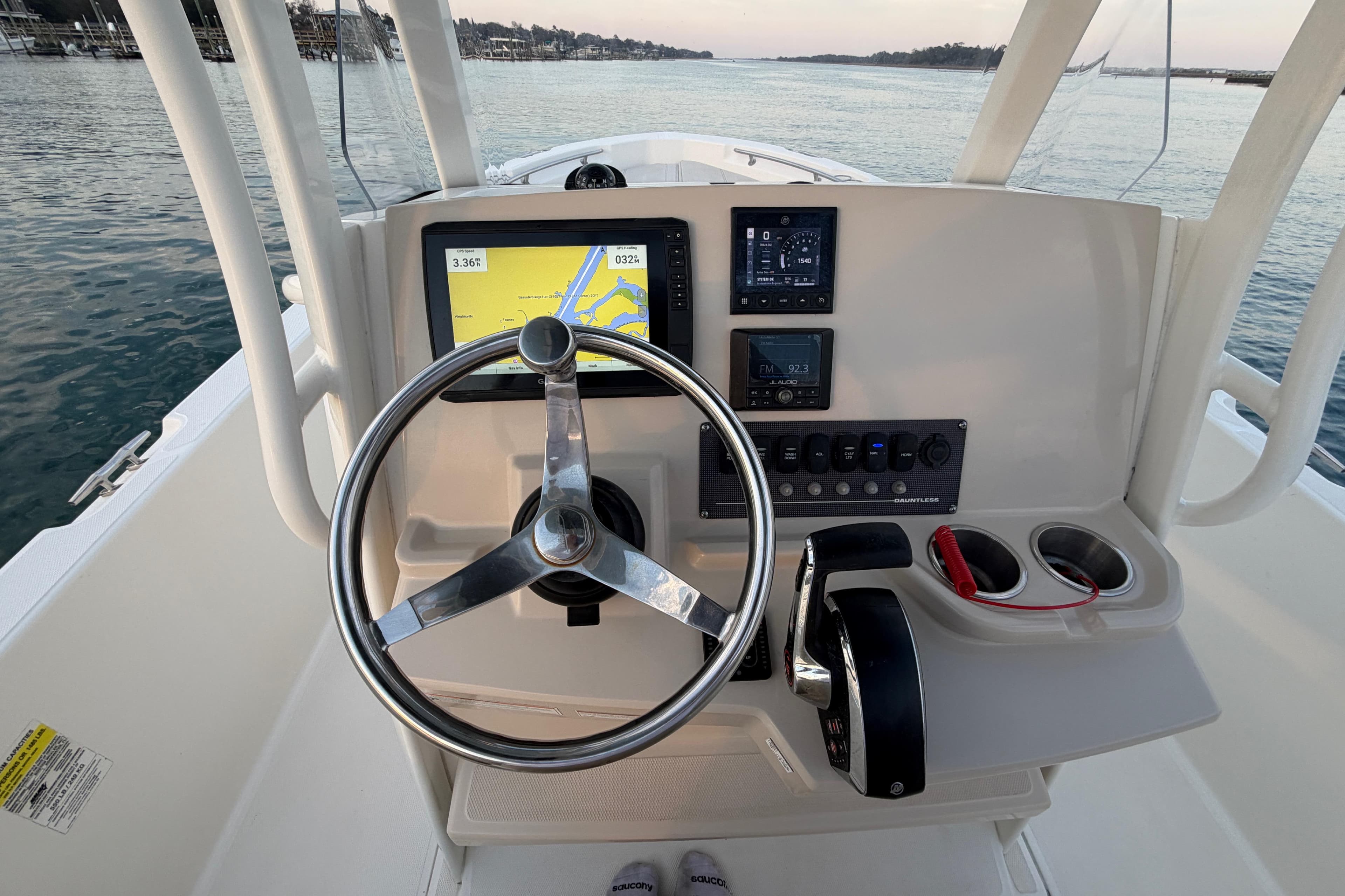 Boston Whaler 220 Dauntless 2023 helm with navigation display and controls on calm water.