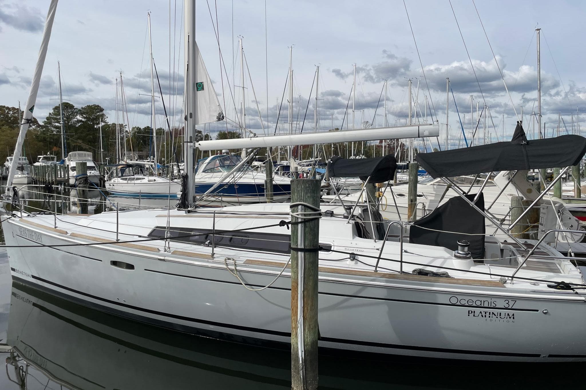 2015 Beneteau Oceanis 37 sailboat docked in a marina, surrounded by other boats.