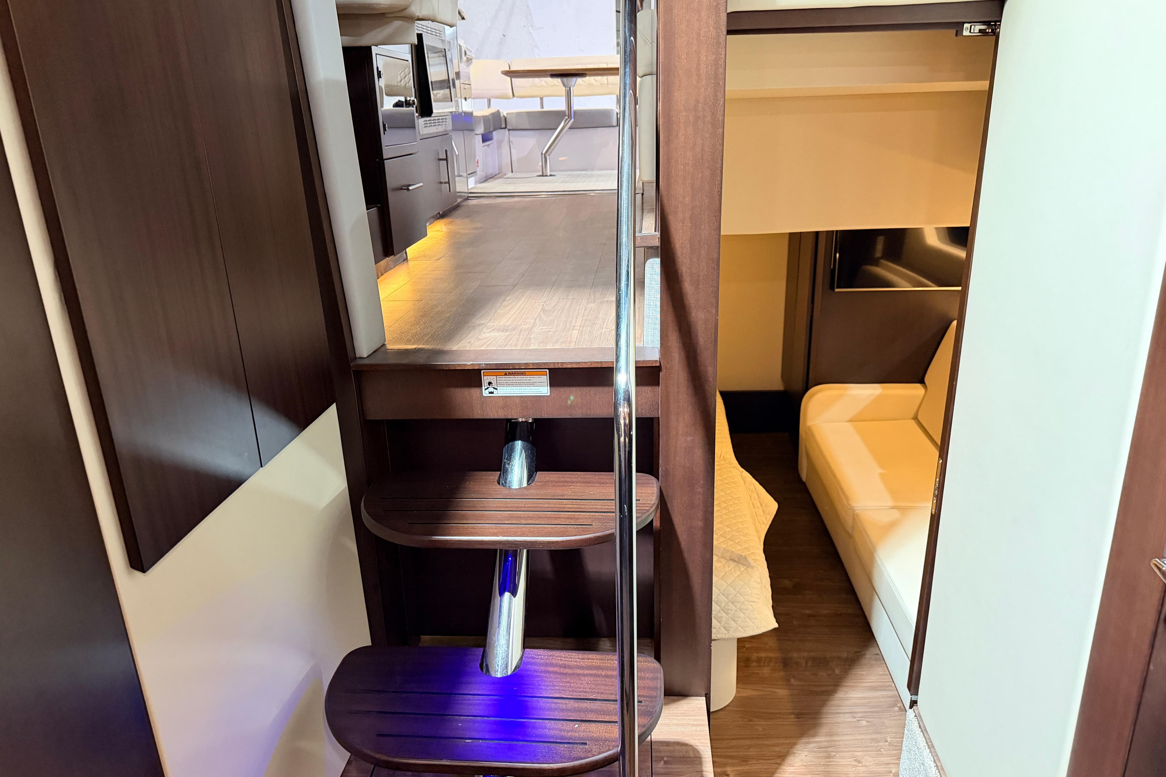Interior view of 2019 Regal 42 Grande Coupe yacht, featuring wooden stairs and modern seating area.