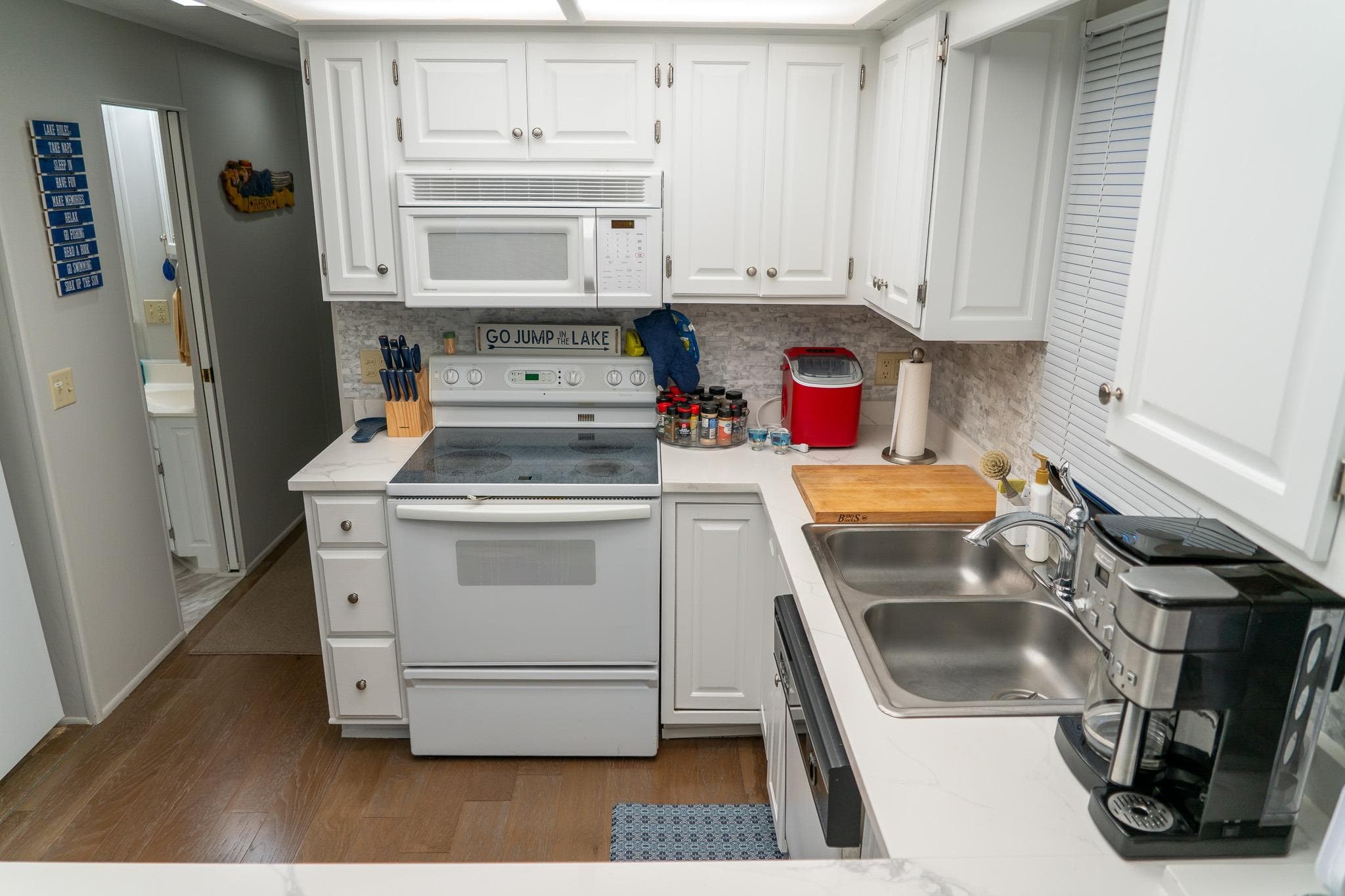 Modern kitchen in 1996 Lakeview 66 x 16 Widebody Houseboat with white cabinets and appliances.