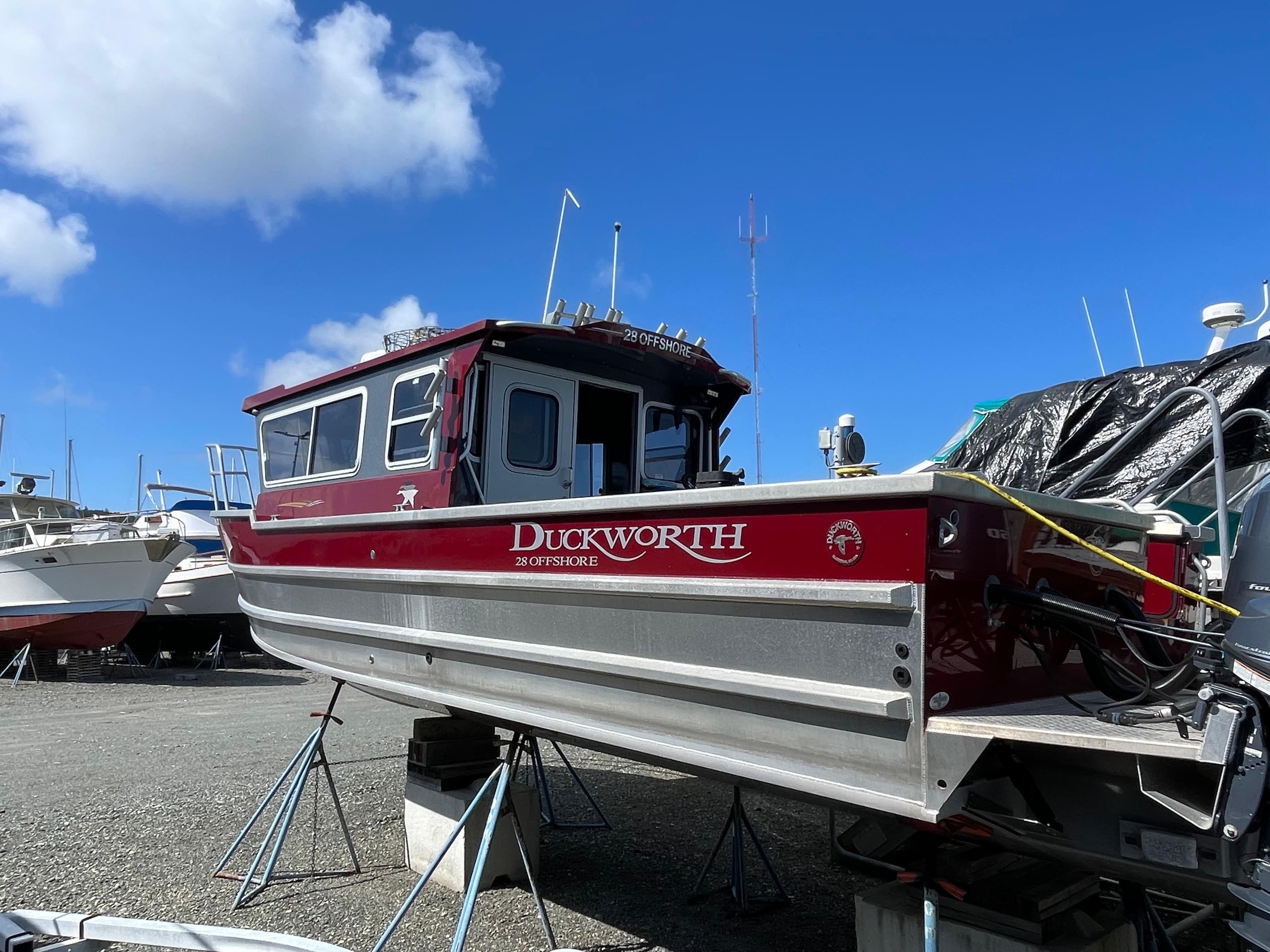 2018 Duckworth 28 Offshore boat on stands, red and silver, under a clear blue sky.