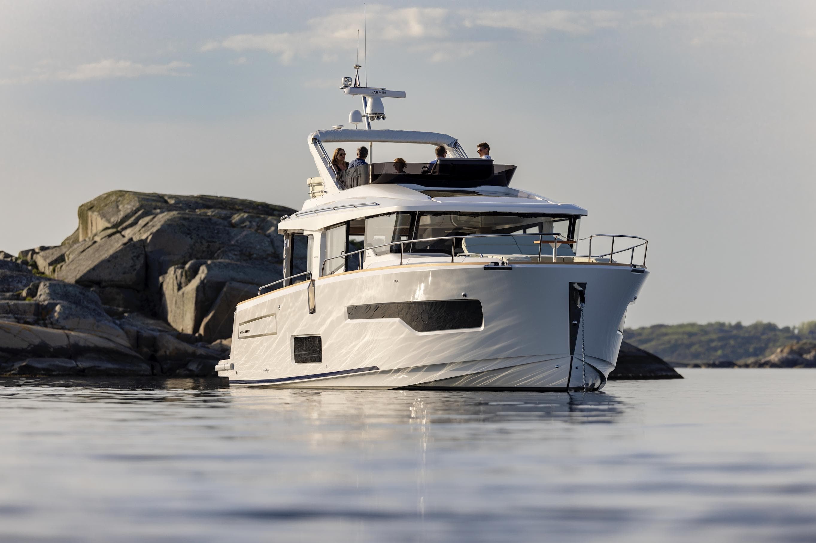 Nimbus 495 Flybridge 2025 yacht cruising near rocky shoreline.
