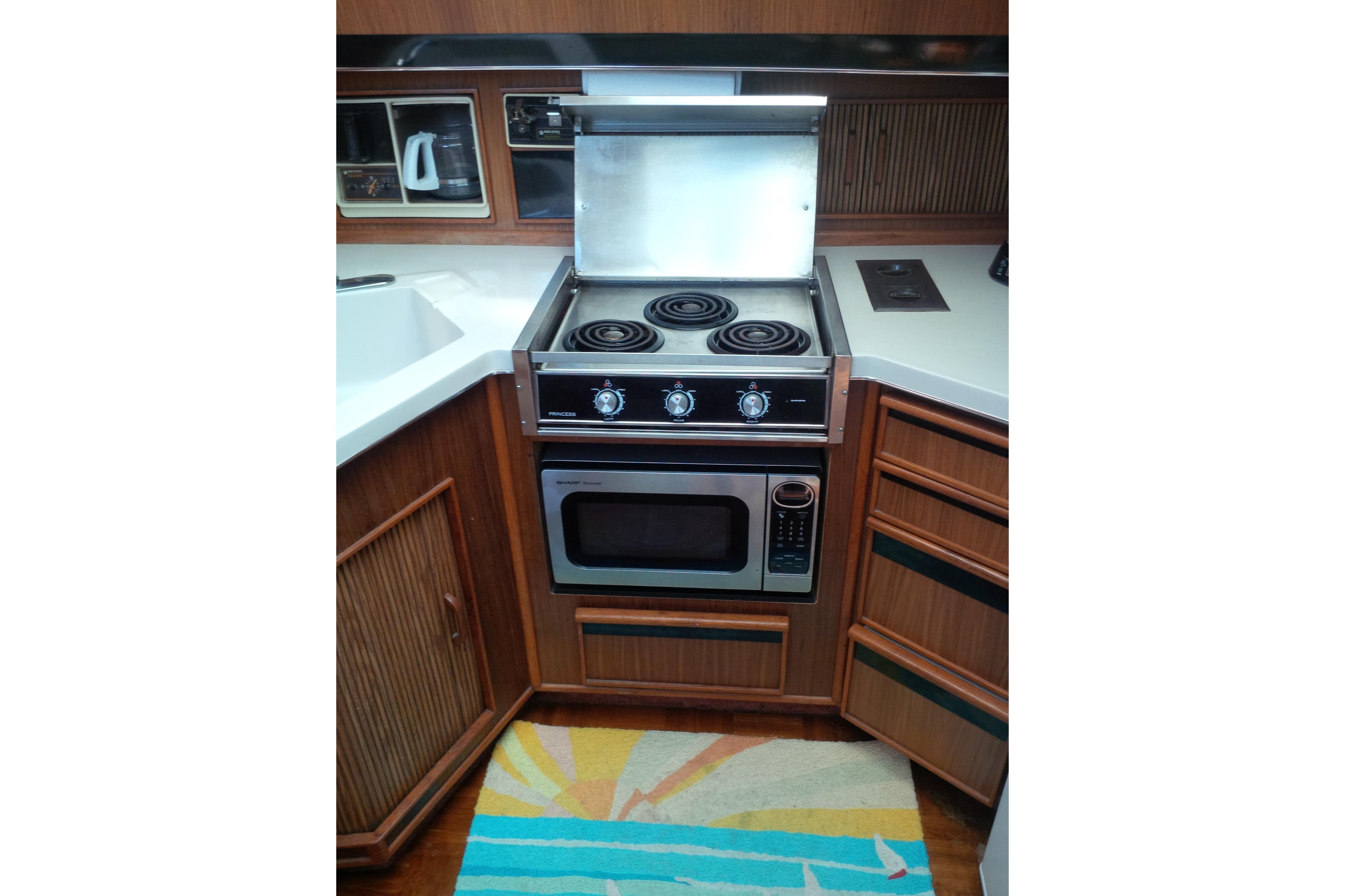 1988 Sea Ray 415 Aft Cabin kitchen with stove, oven, and wooden cabinetry.