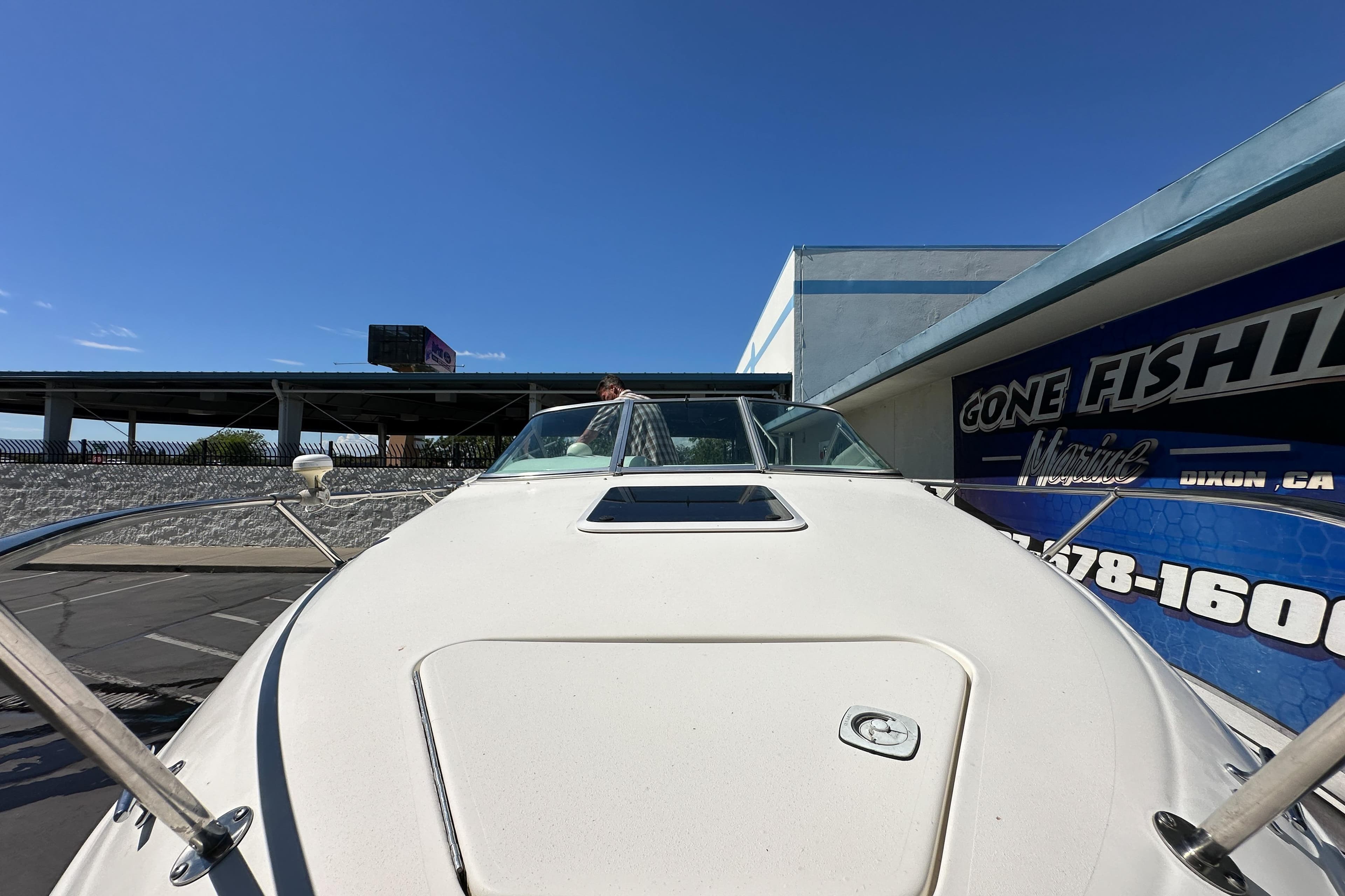 1998 Sea Ray 215 Express Cruiser docked near a "Gone Fishing" sign under clear blue skies.