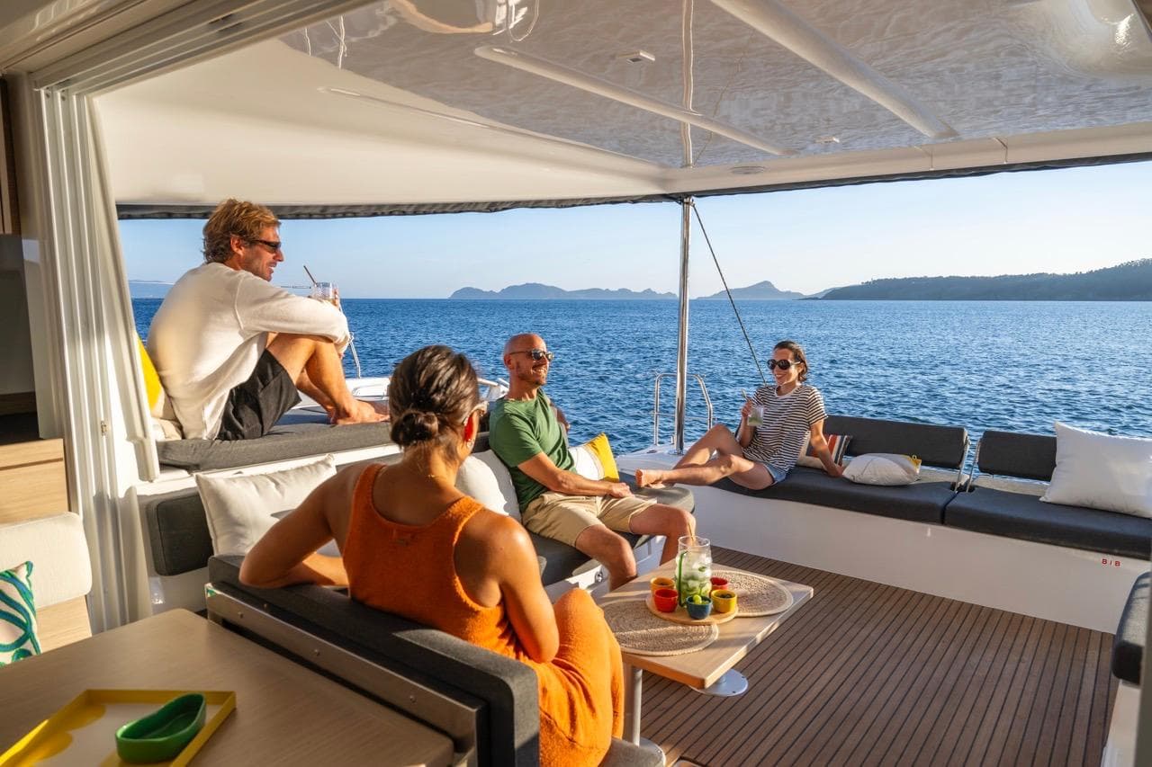 People relaxing on a Lagoon 43 yacht, enjoying the ocean view, 2026 model.