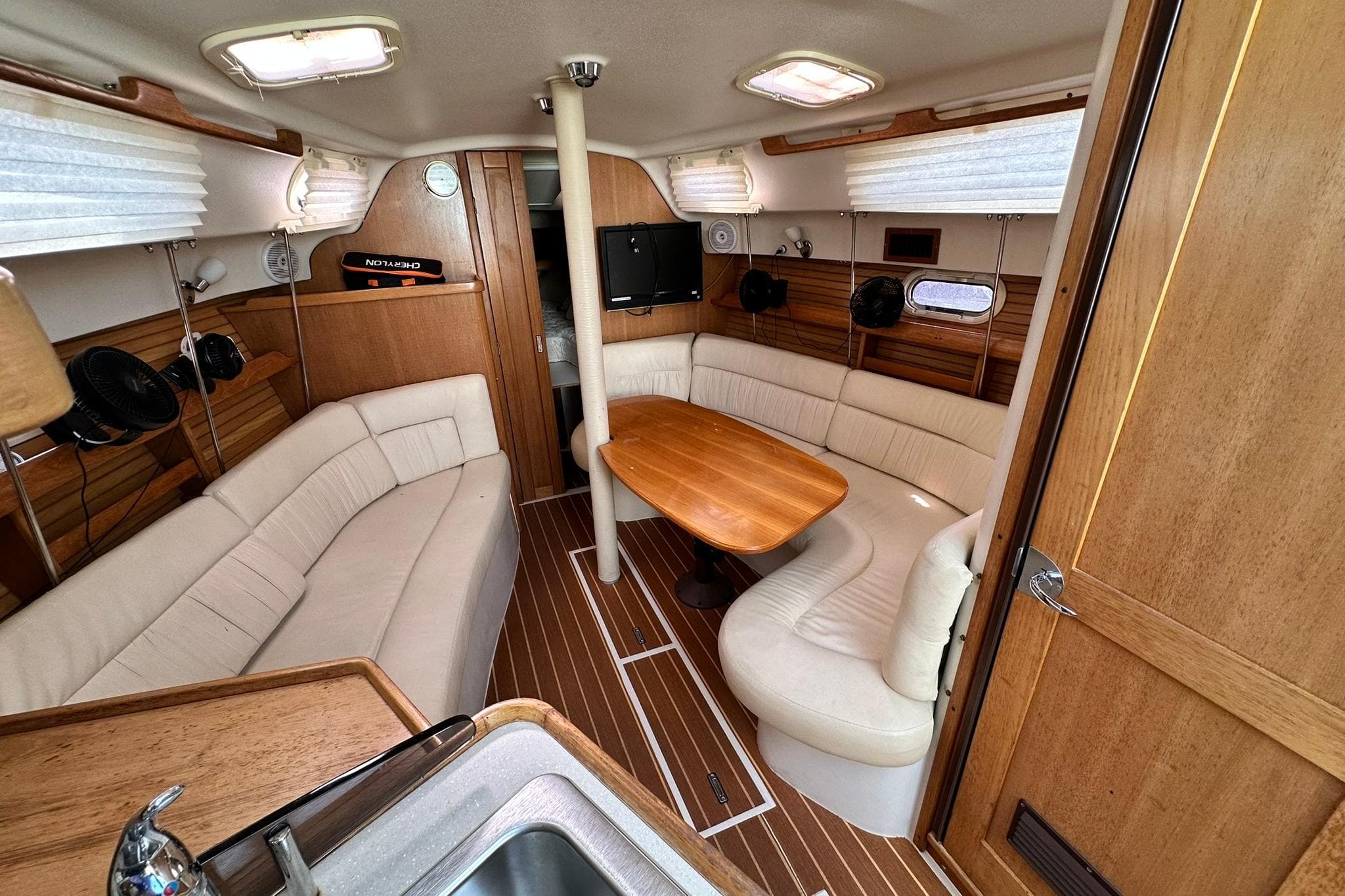 Interior of 2008 Catalina 320 sailboat with cozy seating and wooden table.