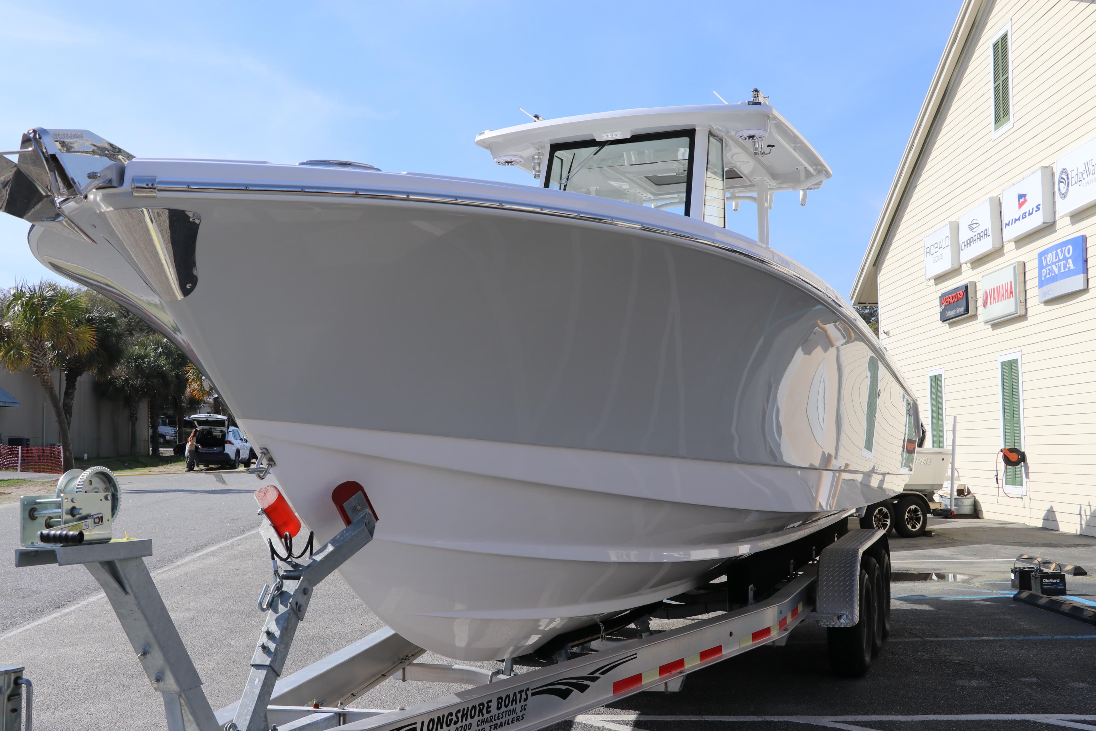 2025 Edgewater 325CC boat on trailer, parked near a building under clear skies.