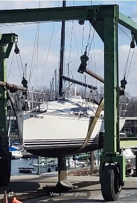Sailboat C&C 99 (2002) being lifted at a marina with a travel lift.