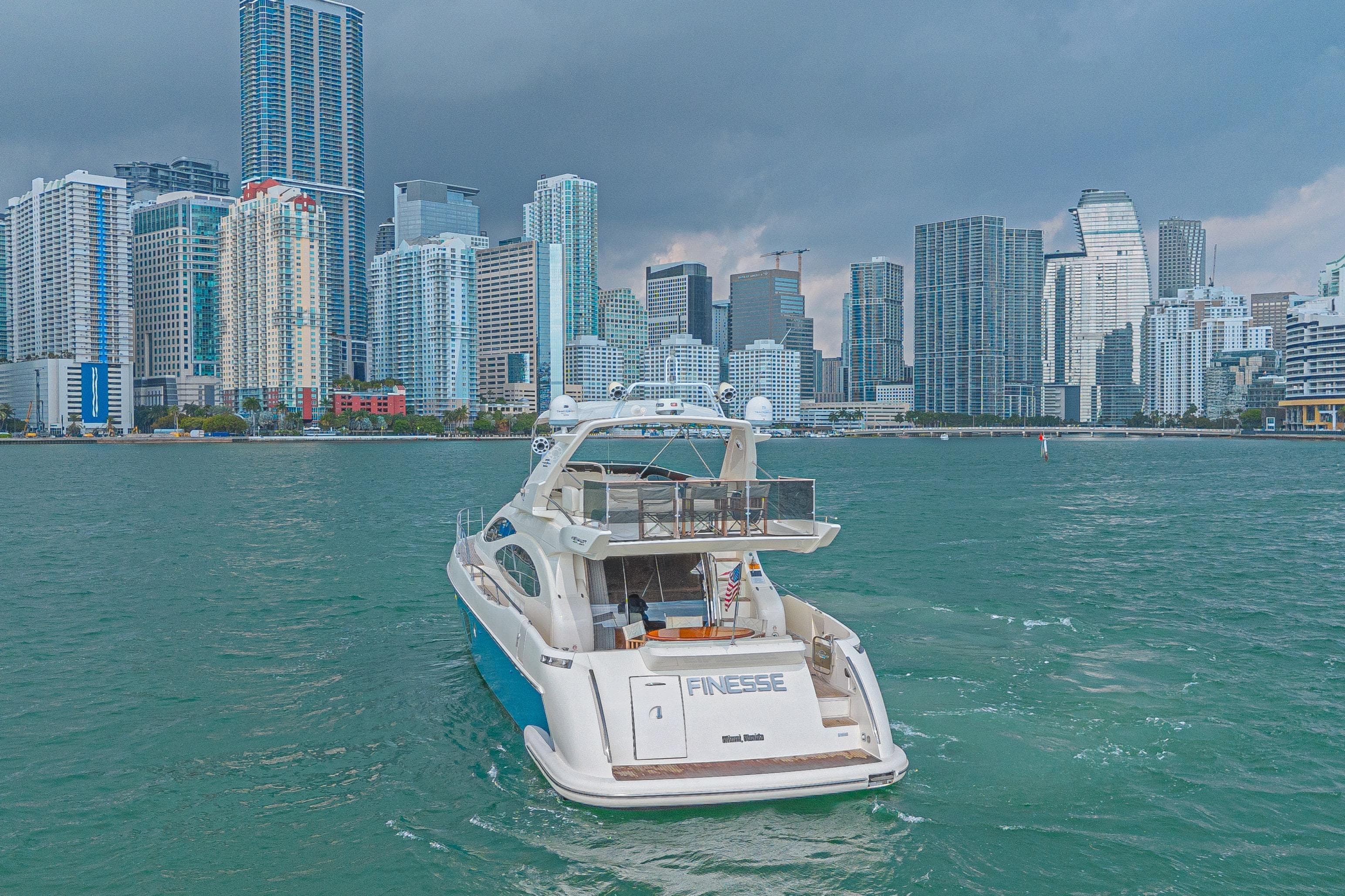 Luxury 2007 Azimut 68E yacht cruising near city skyline under cloudy skies.