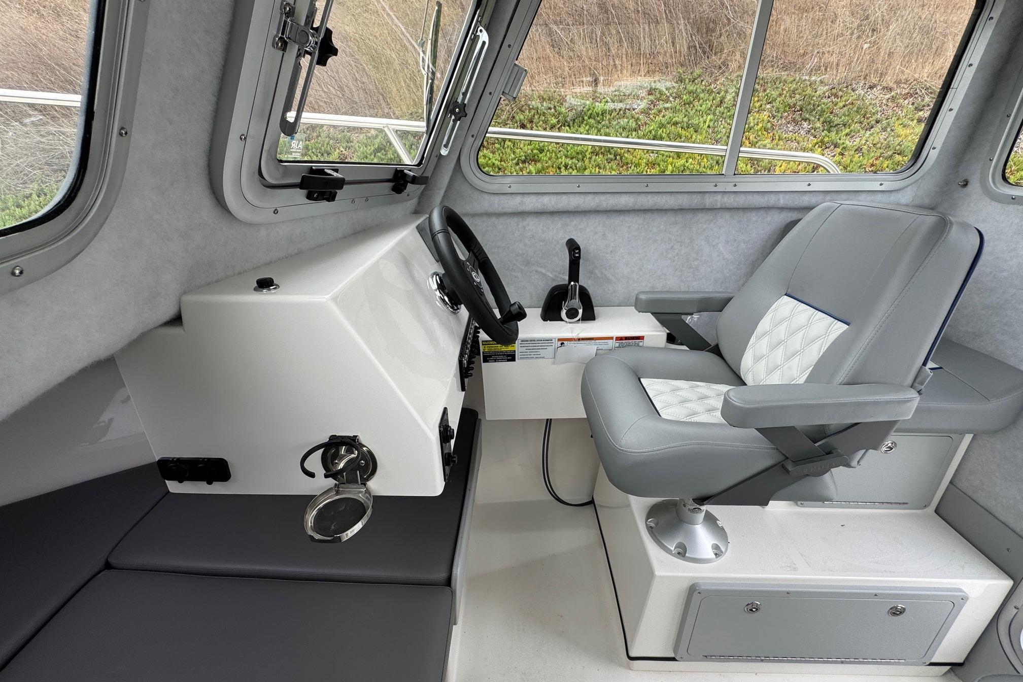 Interior of 2026 Defiance Admiral 220 EX boat with steering console and cushioned captain's chair.