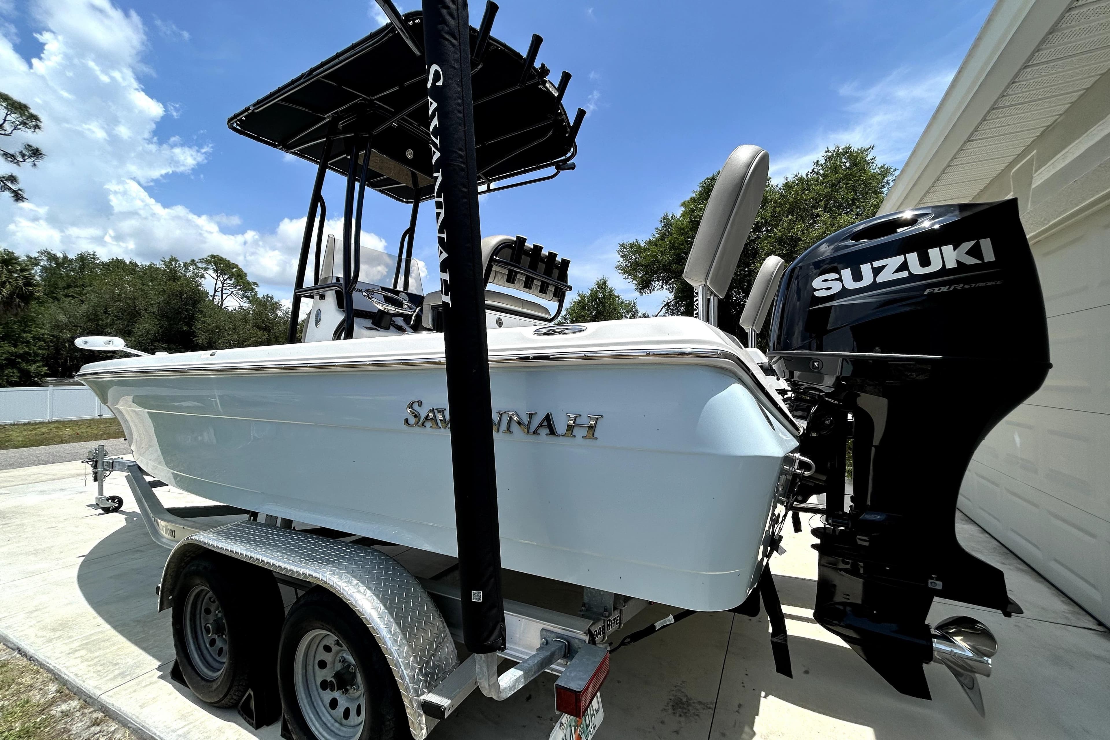 2025 Savannah 210X boat with Suzuki outboard motor on trailer, parked outdoors.