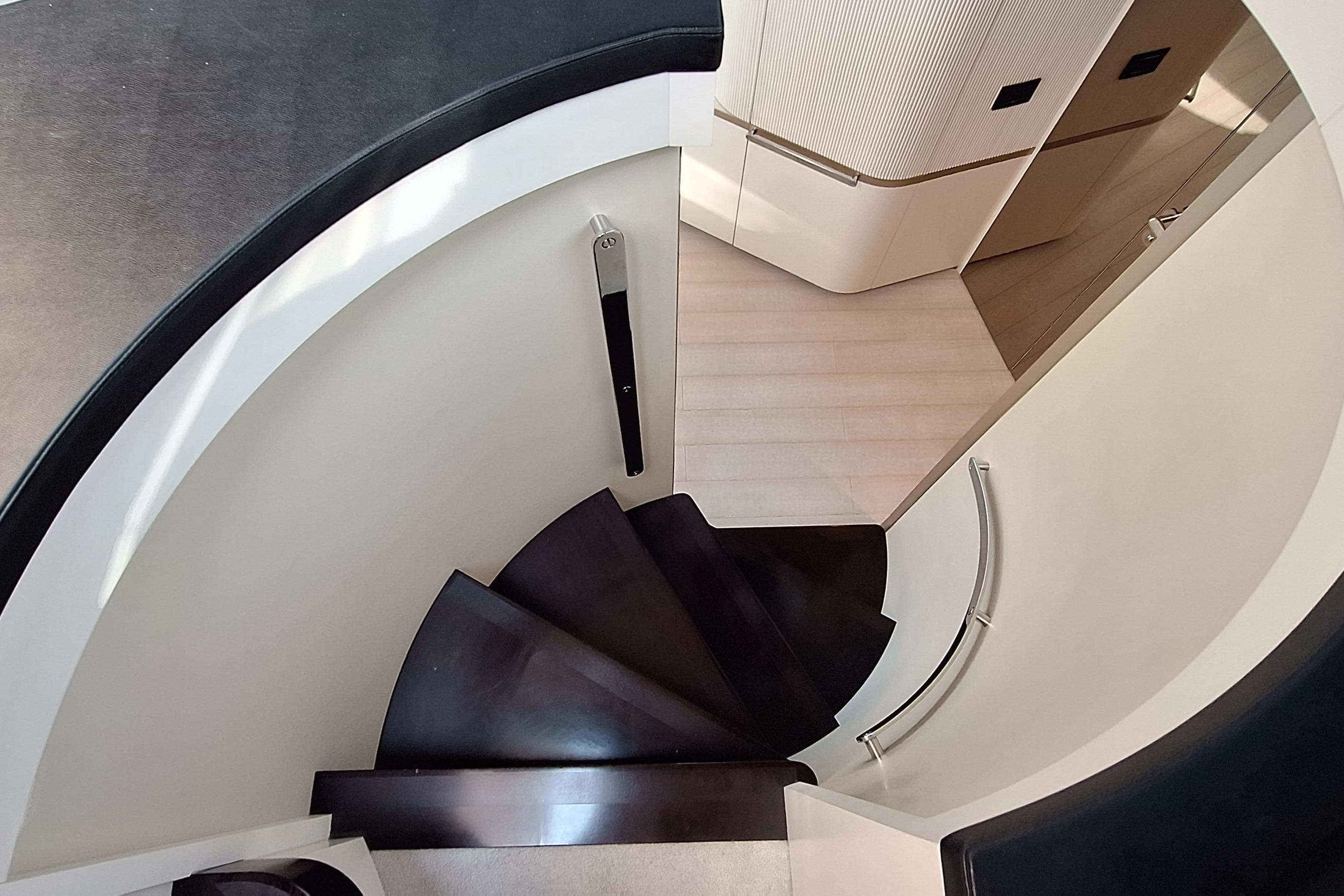 Curved staircase inside 2022 Azimut Magellano 25M yacht, featuring sleek modern design.