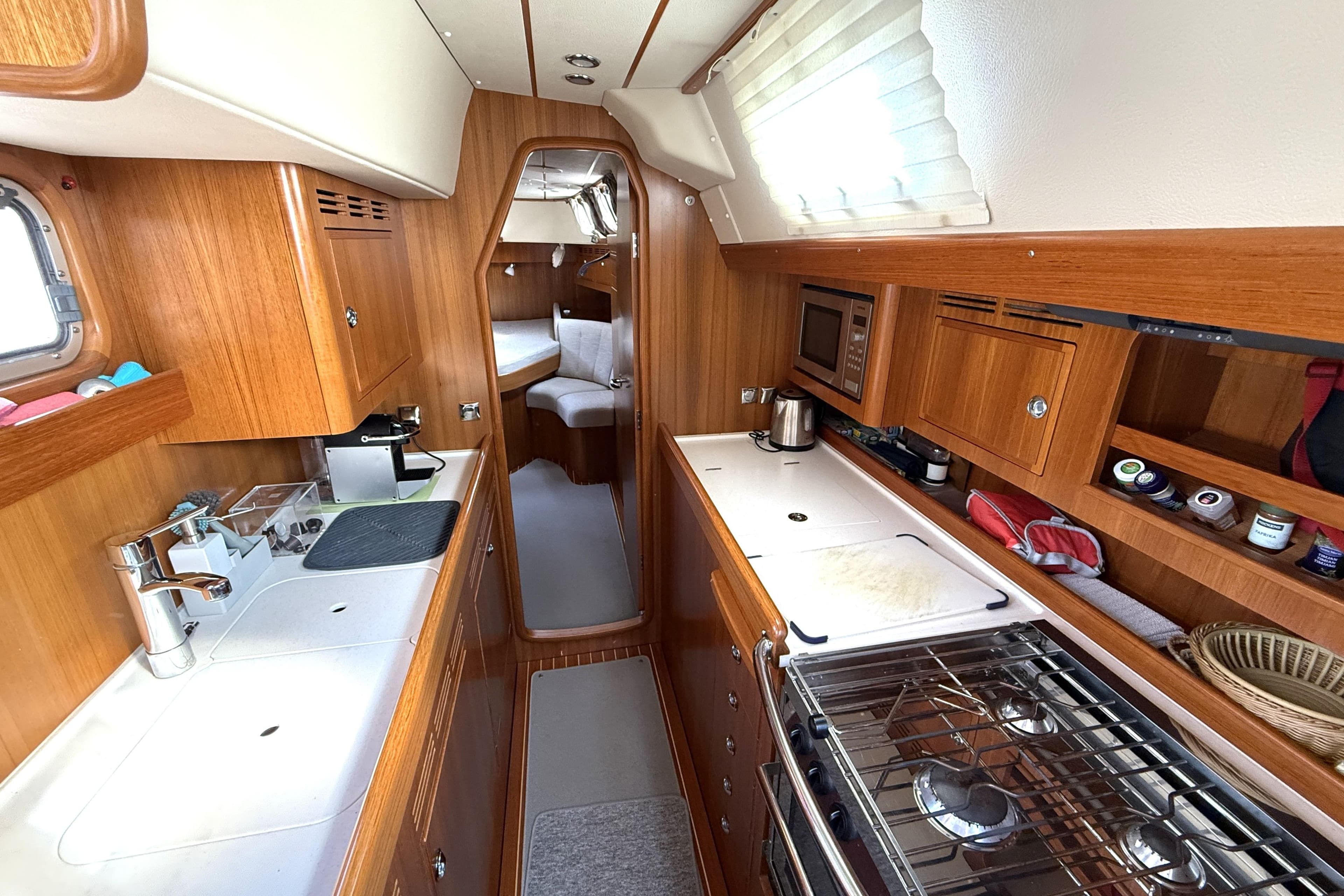 Interior of 2016 Hallberg-Rassy 55 yacht, featuring a well-equipped wooden galley kitchen.