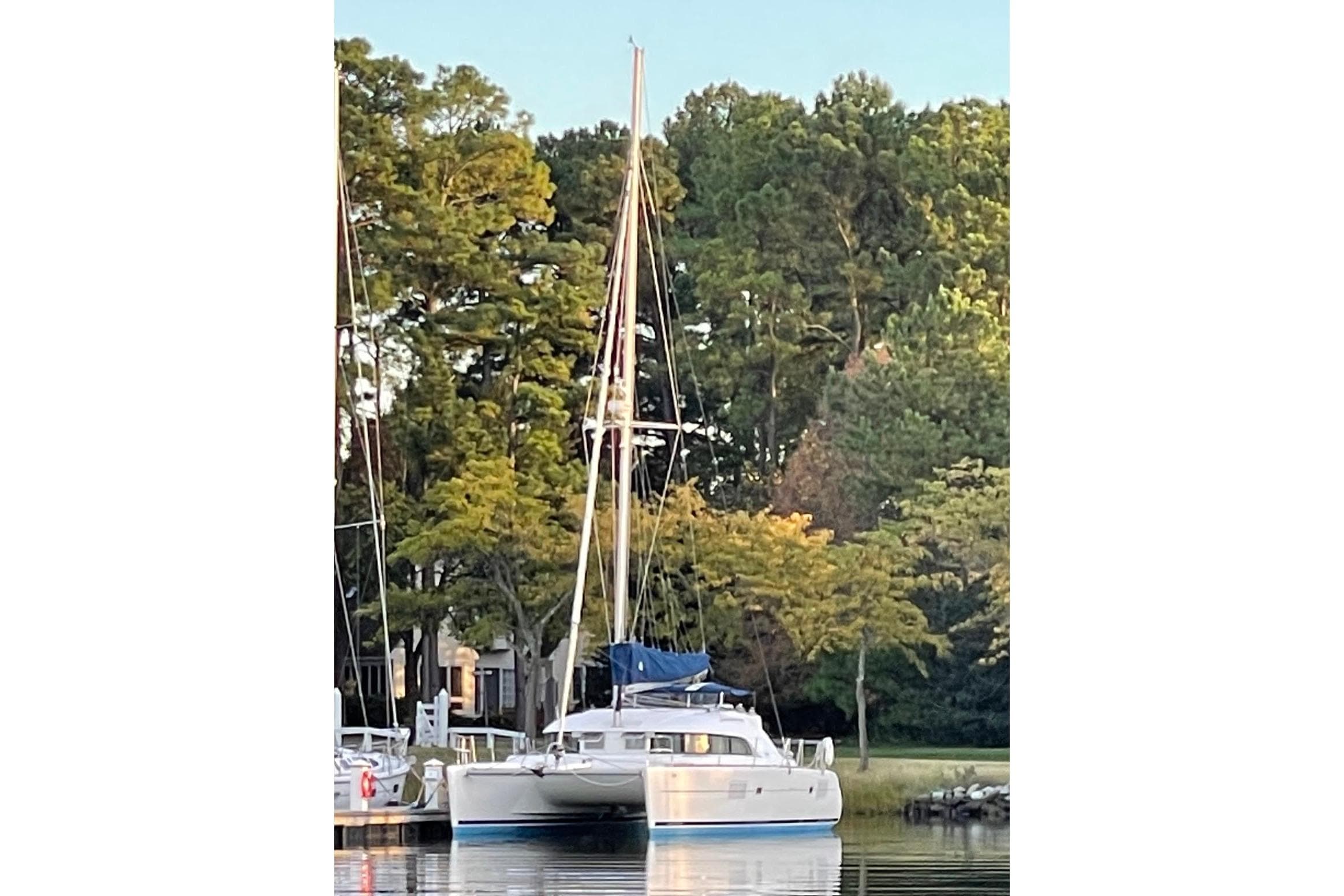 2008 Lagoon 380 S2 catamaran docked by lush green trees.