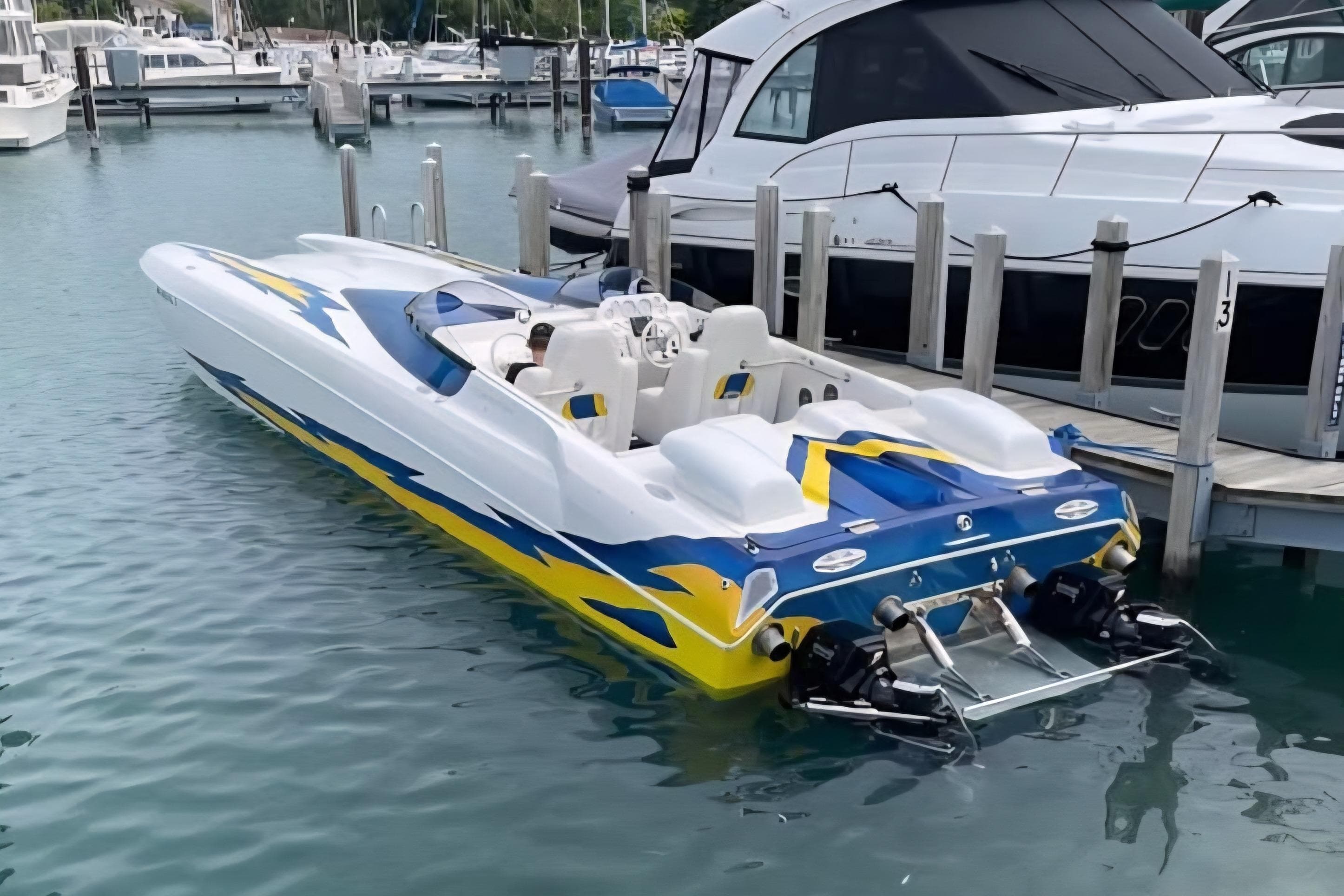 2001 Eliminator 36 Daytona speedboat docked in marina, featuring vibrant blue and yellow design.