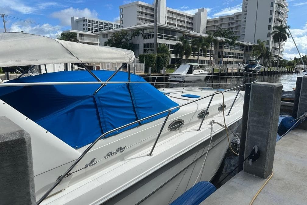 1994 Sea Ray 370 Express Cruiser docked at marina with blue cover.