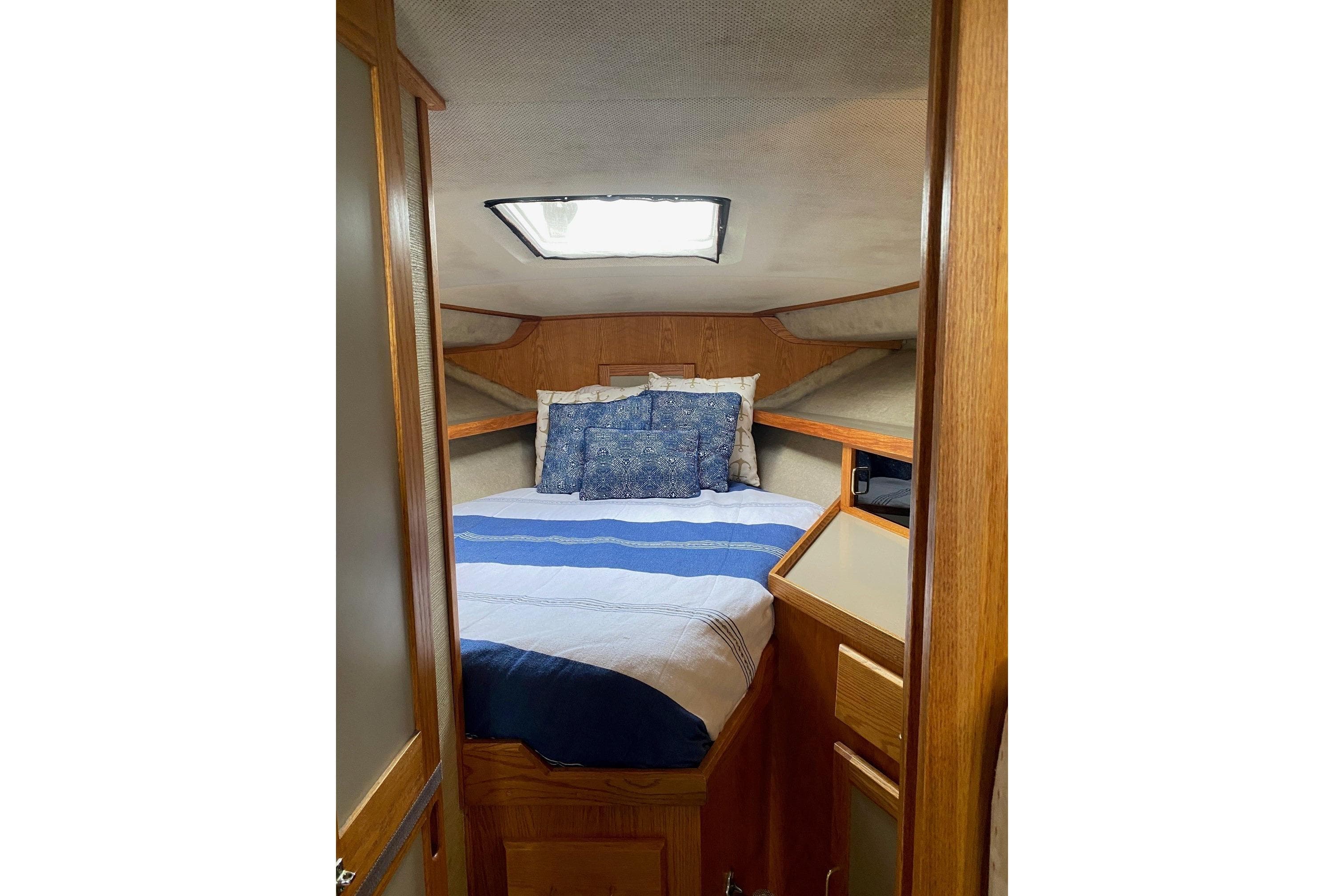 Cozy cabin interior of 1985 Silverton 34 Convertible with bed and wooden cabinetry.